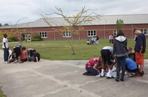 Students learn how to plot points on maps from Marines with Combat Logistics Regiment 27, 2nd Marine Logistics Group during a land navigation class at Brewster Middle School aboard Camp Lejeune, N.C., April 25, 2013. The class taught students the basics of land navigation and how relying on complicated technology is not always a good idea. 