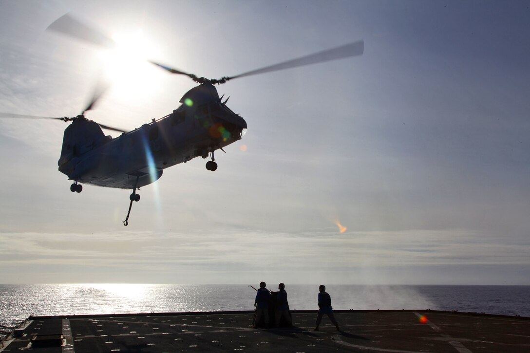 130427-M-VZ265-080 USS RUSHMORE (April 27, 2013) Marines assigned to Transportation Support  Detachment, Combat Logistics Battalion 15, 15th Marine Expeditionary Unit, brace themselves as a CH-46E Sea Knight assigned to Marine Medium Helicopter Squadron 364 (Rein.), 15th MEU, flies above the flight deck during an aerial lift aboard USS Rushmore, April 27. The helicopter support team below conducted a total of seven lifts during the exercise to practice their skills and to refresh the skills of the pilot and crew. The 15th MEU is comprised of approximately 2,400 Marines and sailors and is deployed as part of the Peleliu Amphibious Ready Group. Together, they provide a forward-deployed, flexible sea-based Marine Air Ground Task Force capable of conducting a wide variety of operations ranging from humanitarian aid to combat. (U.S. Marine Corps photo by Cpl. Timothy Childers / Released)