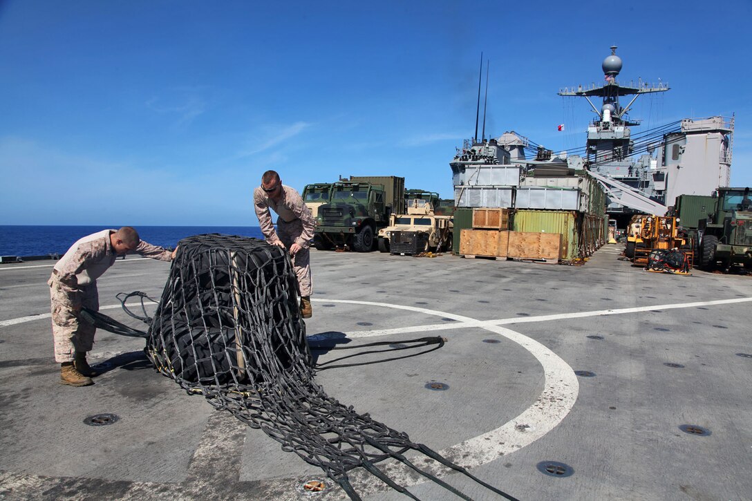 130427-M-VZ265-009 USS RUSHMORE (April 27, 2013) Marines assigned to Transportation Support  Detachment, Combat Logistics Battalion 15, 15th Marine Expeditionary Unit, secure a cargo net over three tires before a helicopter support team conducts an aerial lift aboard USS Rushmore, April 27. The team of four conducted a total of seven aerial lifts to refresh their skills. To assist them, the pilot and crew of a CH-46E Sea Knight assigned to Marine Medium Helicopter Squadron 364 (Rein.), 15th MEU, participated in the exercise to bolster both the Marines on the flight deck and their own training. The 15th MEU is comprised of approximately 2,400 Marines and sailors and is deployed as part of the Peleliu Amphibious Ready Group. Together, they provide a forward-deployed, flexible sea-based Marine Air Ground Task Force capable of conducting a wide variety of operations ranging from humanitarian aid to combat. (U.S. Marine Corps photo by Cpl. Timothy Childers / Released)