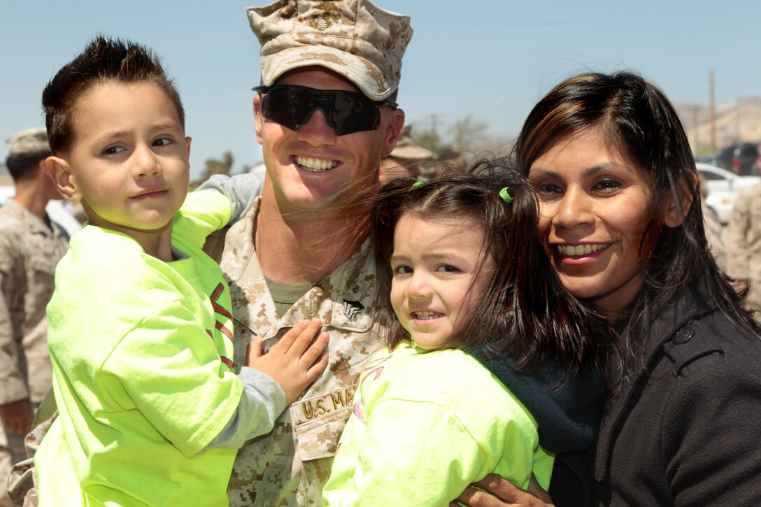 Sgt. John Hukaba, motor transport driver,  2nd Battalion, 7th Marine Regiment, holds his son, Tobias, 4, and daughter, Eliana, 2, for the first time in seven months, during the battalion's homecoming ceremony at Del Valle Field April 9, 2013. 