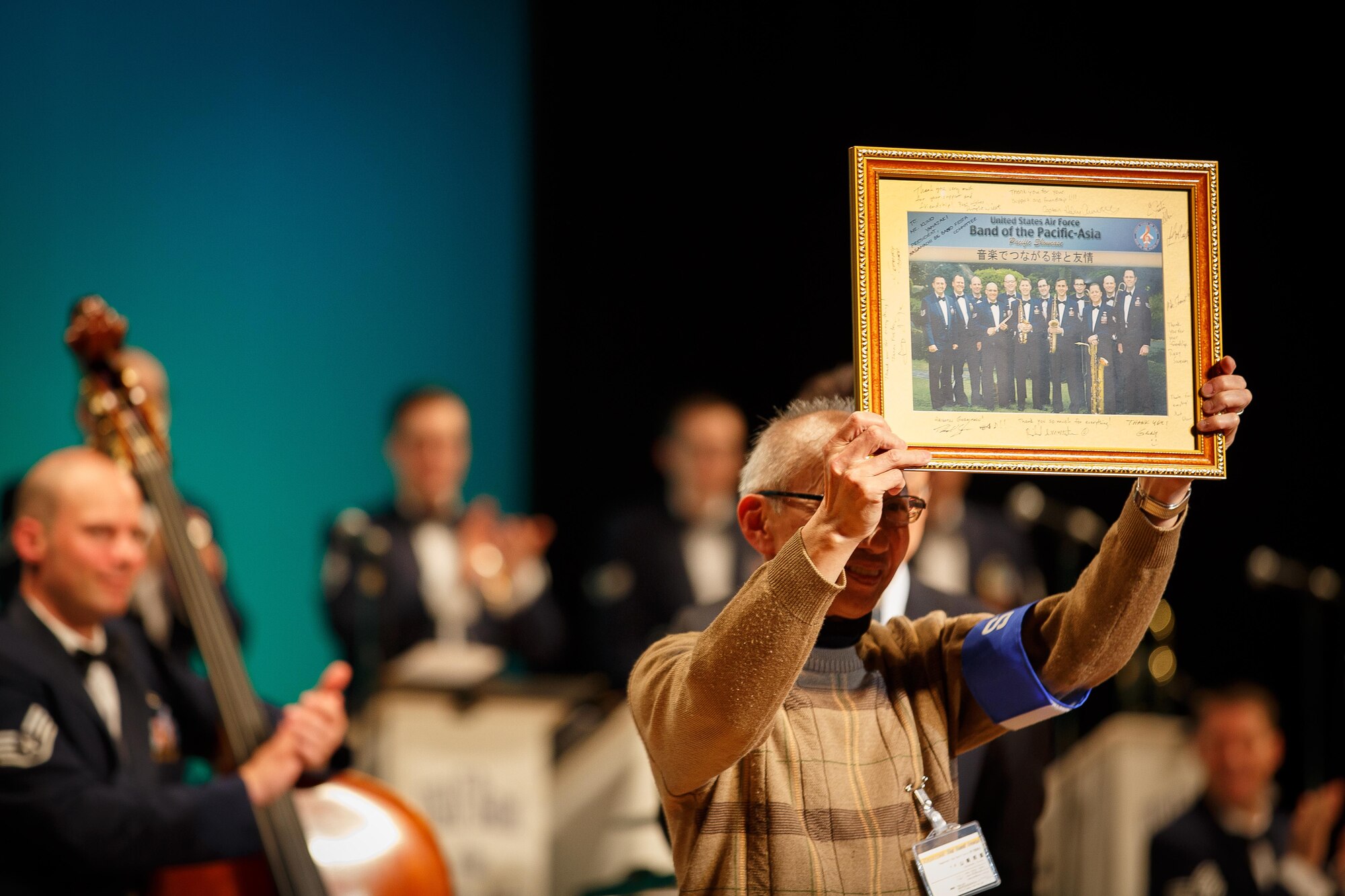 Yamazaki-san, president of the Nagamachi Big Band Festival, accepts a commemorative photo from the  U.S. Air Force Band of the Pacific-Asia to showcase their international partnership in Sendai, Japan April 21, 2013. The band completed a 3-day tour of various cities in Japan April 20 through 22, to remember the victims of the earthquake and tsunami that ravaged the area approximately two years ago. (U.S. Air Force photo/Staff Sergeant Josh Voyles)