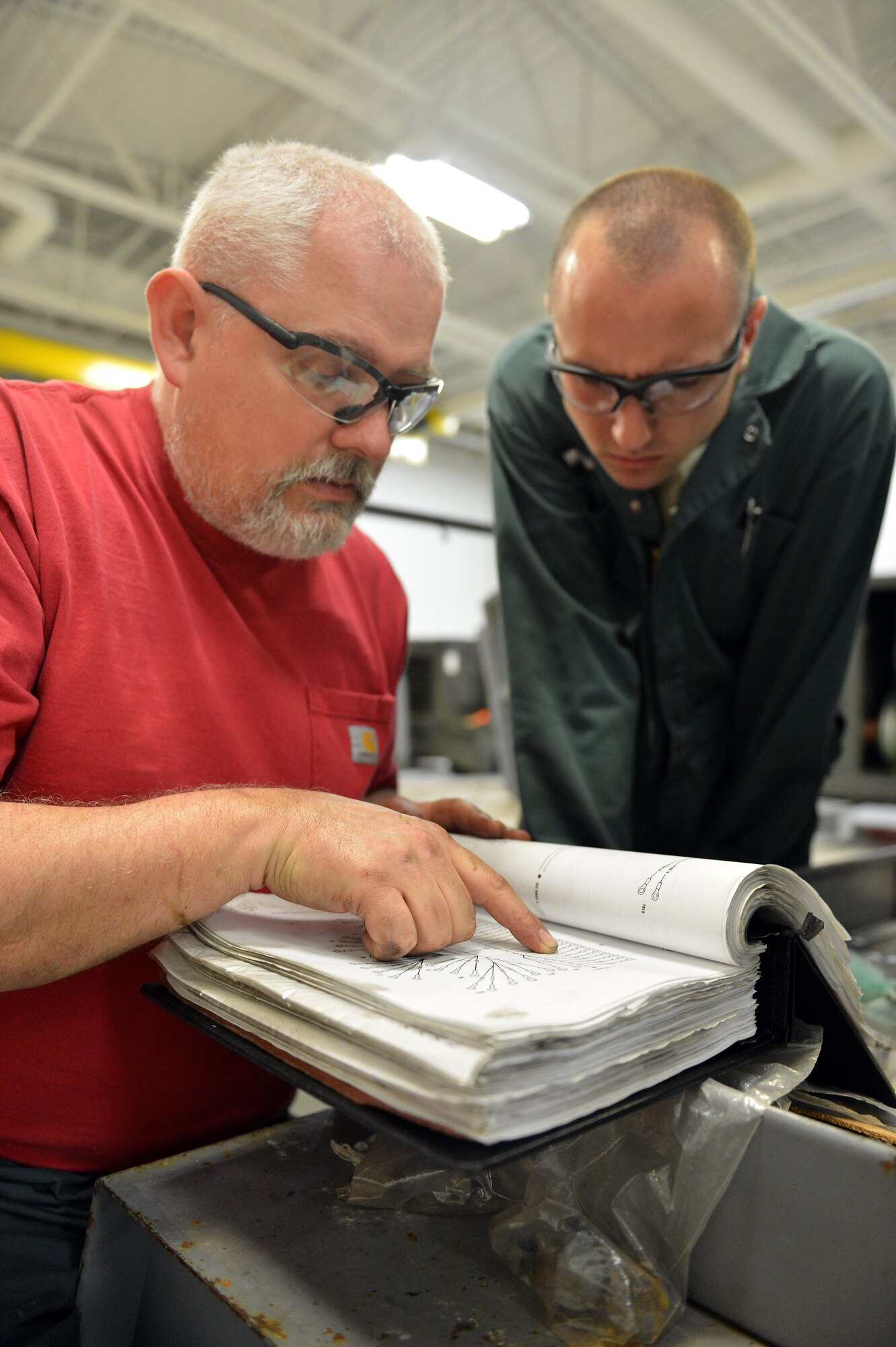 Greg Robbins, 62nd Maintenance Squadron Aerospace Ground Equipment power systems support technician (left), and Airman 1st Class Jared Williams, 62nd MXS AGE technician (right), look over an Air Force technical order prior to performing maintenance on a -86 diesel generator, April 26, 2013 at Joint Base Lewis-McChord, Wash. Robbins is an AGE shop supervisor responsible for training AGE technicians and perfoming maintenance oversight. (U.S. Air Force photo/Airman 1st Class Jacob Jimenez)