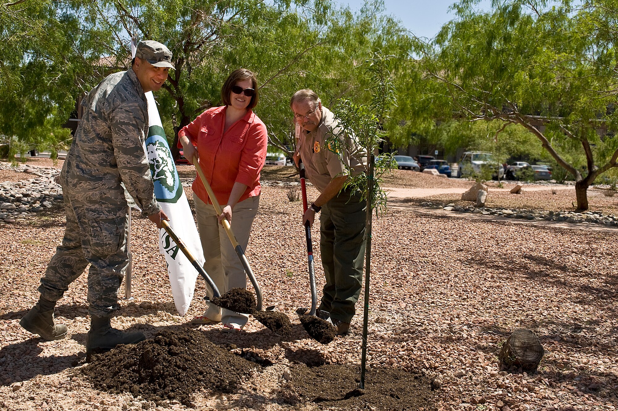 Col. Aaron Young, 99th Civil Engineer Squadron commander; Ann Bedlion, 99th CES natural resource manager; and Mark Blankensop, Nevada Division of Forestry Southern Regional forester, shovel dirt onto a newly planted tree during the Earth Day Tree Planting Ceremony April 25, 2013, at the Maj. Gen. Billy McCoy Environmental Grove at Nellis Air Force Base, Nev. The Nevada Division of Forestry has designated Nellis AFB as a Tree City USA community for the past 19 years. (U.S. Air Force photo by Senior Airman Matthew Lancaster)