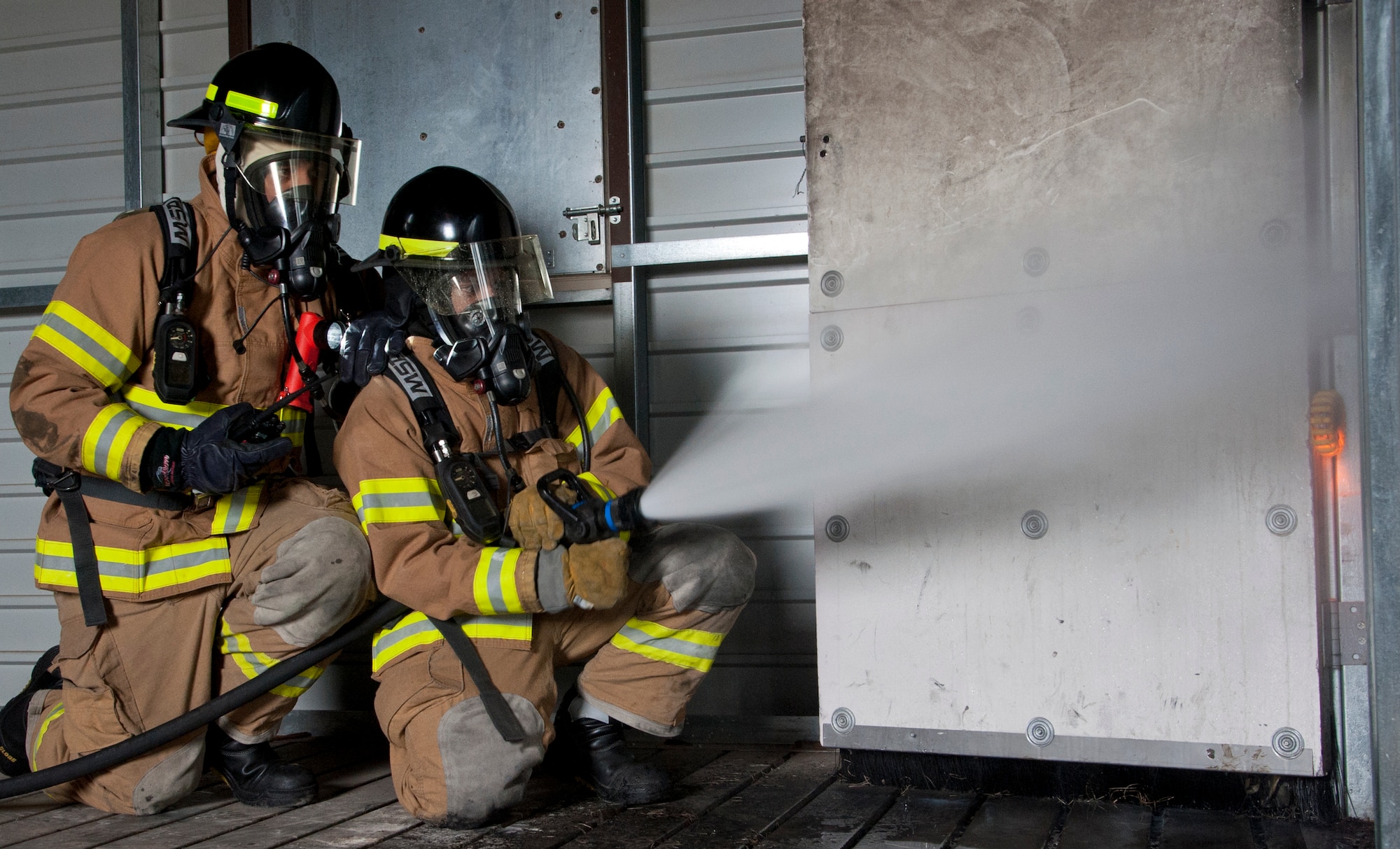 ALTUS AIR FORCE BASE, Okla. - Firefighters from the 97th Civil Engineer Squadron Fire Department spray water from an Ultra High Pressure system in the fire training building during a training exercise at the burn pit, April 25. Members of the 97th CES Fire Department trained with the new P-34 Rapid Intervention Vehicle, which is the newest addition to the Air Force’s crash response fleet and the first vehicle to use Ultra High Pressure firefighting technology. The P-36 is not only more cost efficient, it is also making the job of battling fires safer. (U.S. Air Force photo by Senior Airman Kenneth W. Norman)