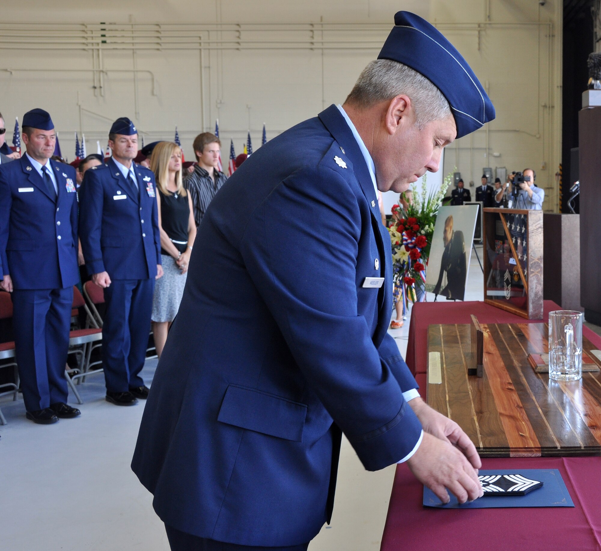 Lt. Col. John Keeler, 306th Rescue Squadron commander, places chief master sergeant stripes on a table during the memorial ceremony of Chief Master Sgt. Nicholas McCaskill, April 27, 2013. McCaskill was killed in Afghanistan April 6, 2013 while he was performing his civilian job as a security contractor. He was promoted to chief master sergeant on Feb. 1, 2013 and was going to have his formal chief pinning ceremony during the May Unit Training Assembly weekend. (U.S. Air Force Photo/ Staff Sgt. Sarah Pullen)