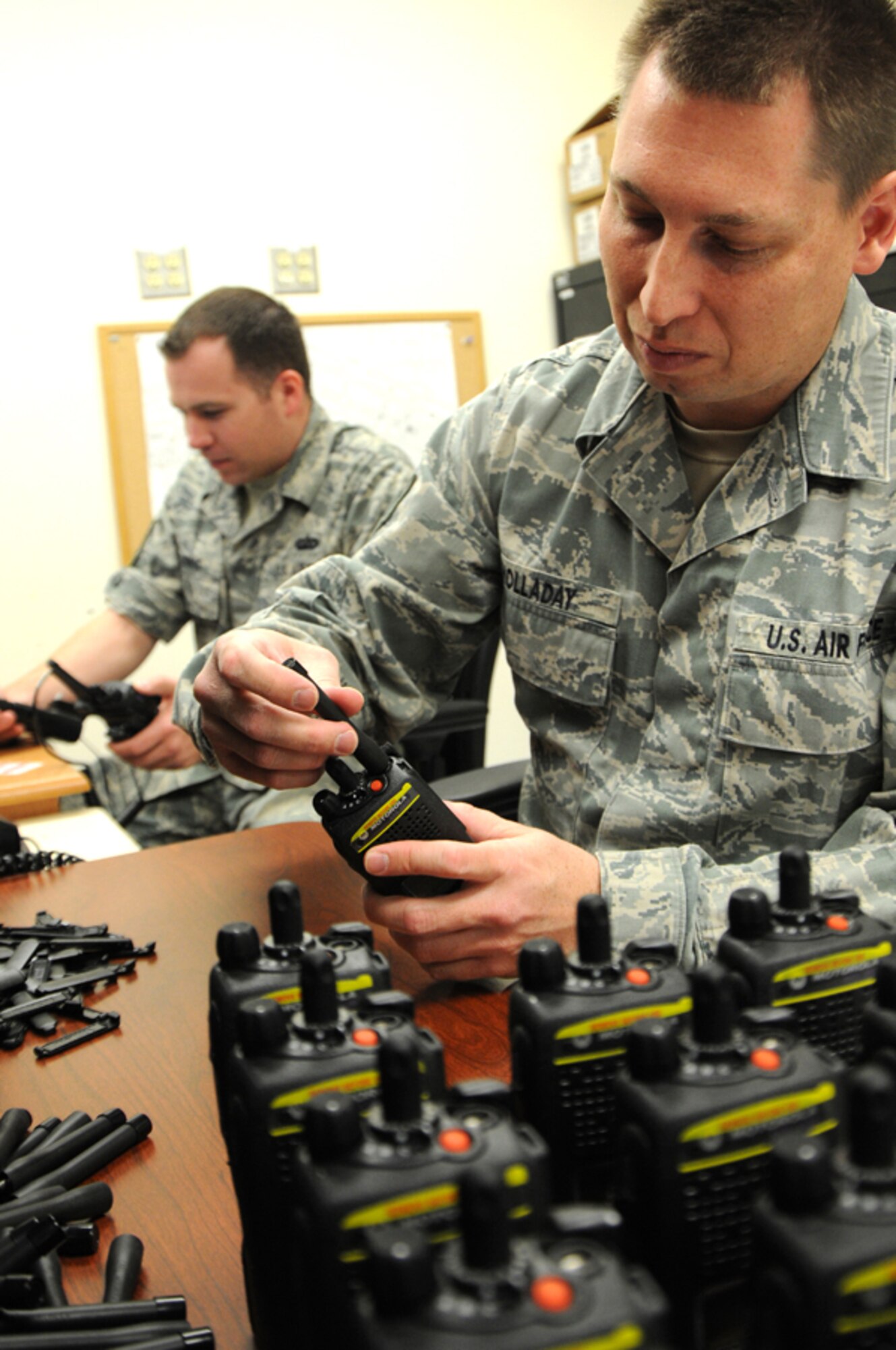 As more than 400 new radios arrived from National Guard Bureau on Apr. 24, Staff Sgt. Mark Holladay, foreground, from the 124th Communications Flight, prepares the encrypted radios by attaching clips, antennas and the serial number system and passes each radio for the final encrypting process performed by Tech. Sgt. Robert Kolenic. (U.S. Air Force photo by Tech. Sgt. Becky Vanshur)