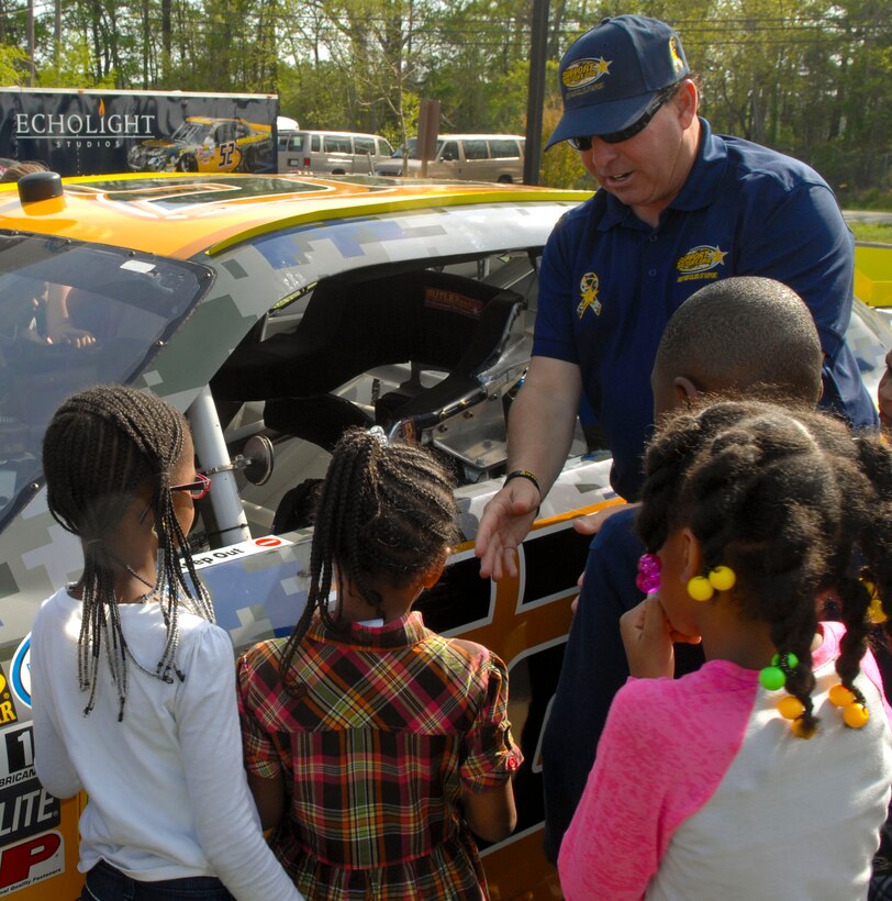 Dell Hamilton, Support Military organization co-founder, helps a child settle into a former NASCAR competition vehicle at Langley Air Force Base, Va., April 24, 2013. The number 52 vehicle visited Langley’s  flightline, community center and the Bethel Youth Center. (U.S. Air Force photo by Airman 1st Class Austin Harvill/Released)