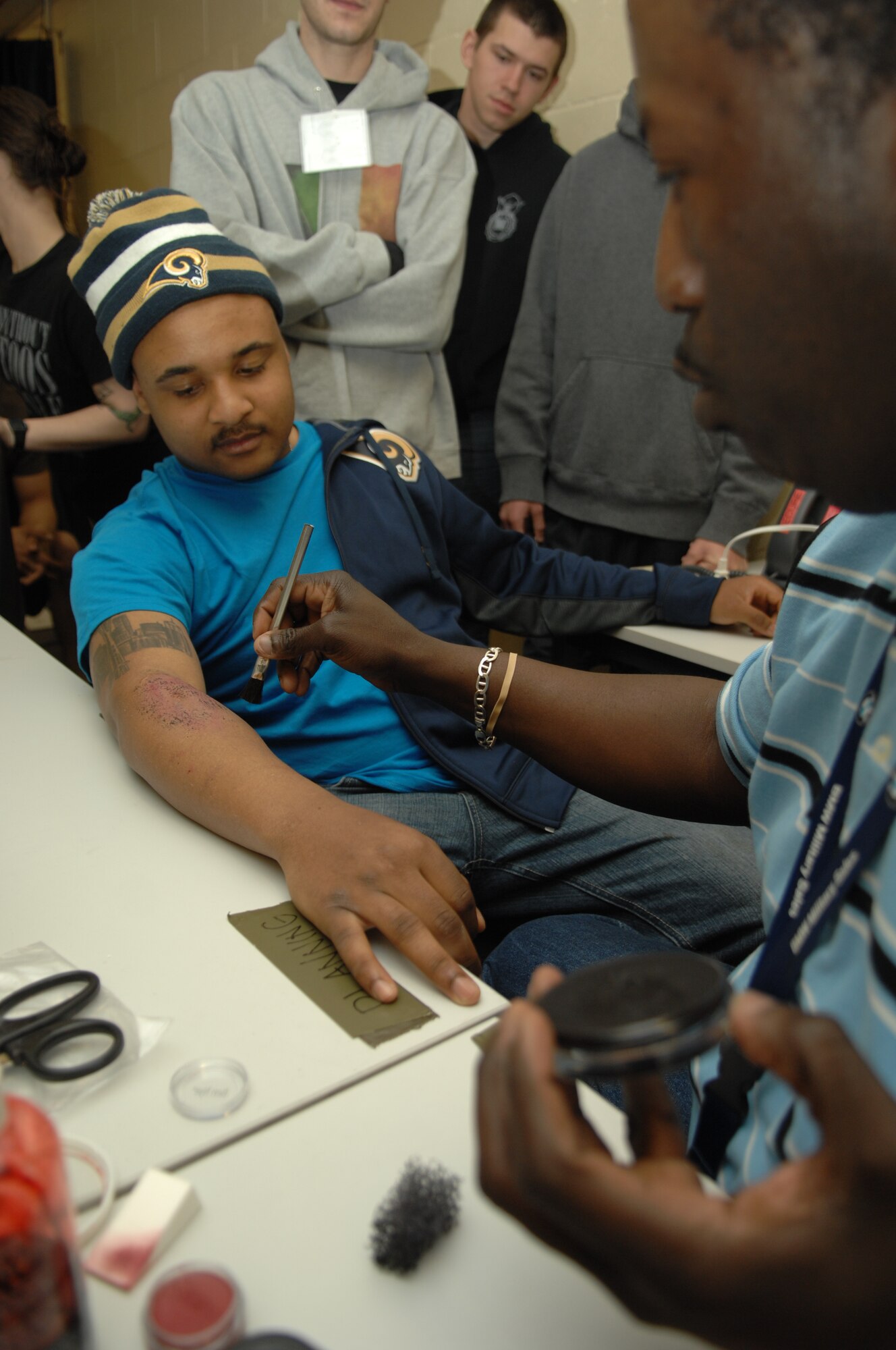 From left, Airman 1st Class Grant Gipson, 100th Security Forces Squadron patrolman from Seattle, has his arm painted to look like it was injured by William Goodwin, simulation operator from Philadelphia, for an exercise April 29, 2013, on RAF Mildenhall, England. The exercise required emergency personnel to respond to a scene involving seven casualties and one death. [(Editor’s note: This image is from an exercise and does not depict any real world event.)(U.S. Air Force photo by Airman 1st Class Dillon Johnston/Released)]