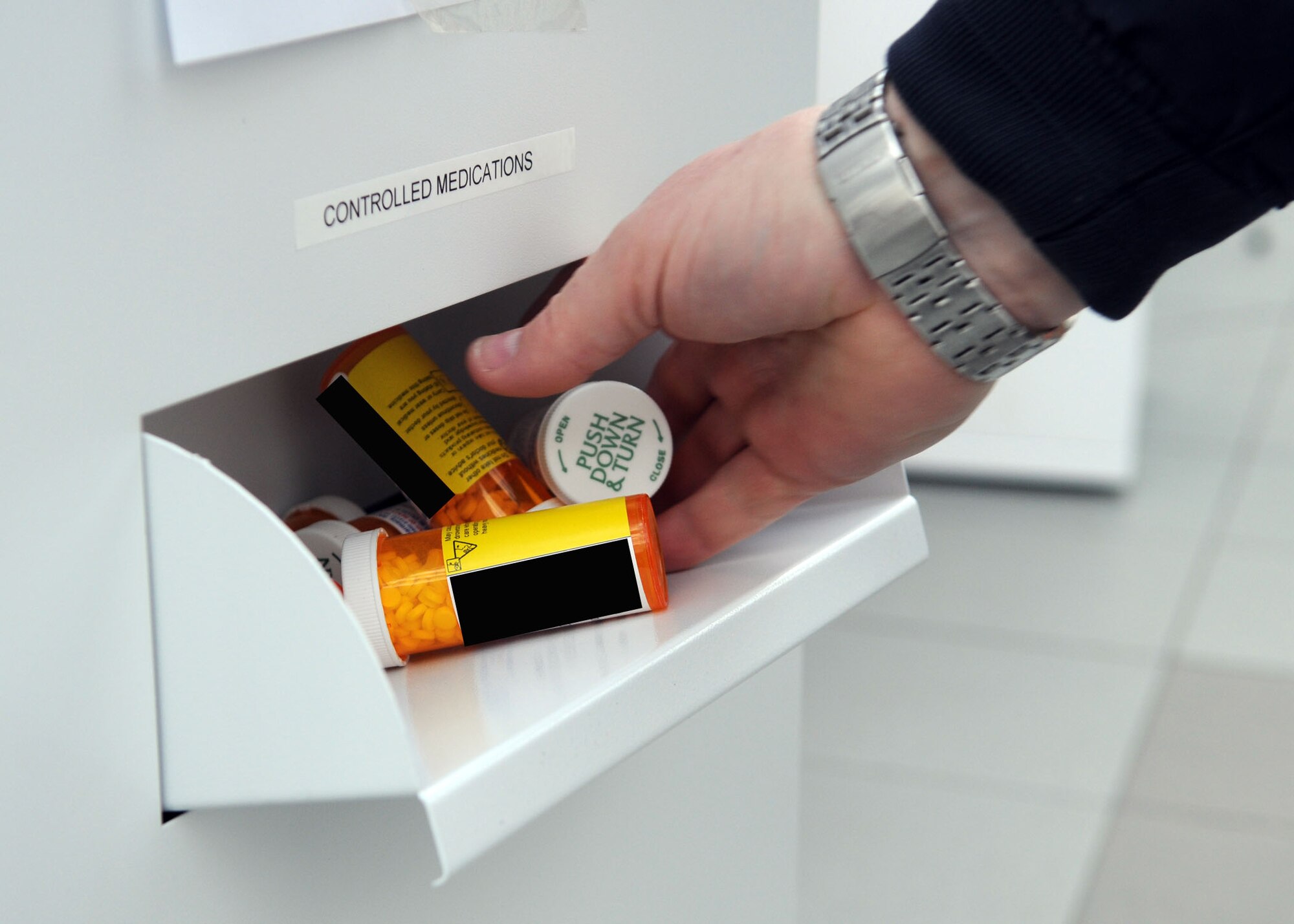 A Team Mildenhall member drops off expired medication at the RAF Mildenhall Drug Demand Reduction program drug collection point at The Exchange April 27, 2013, at RAF Mildenhall, England.  The DDR turn-in point gave base patrons a safe place to drop off their unused and expired medications. [(Photo altered for privacy purposes.) (U.S. Air Force photo by Staff Sgt. Tabitha M. Lee/Released)]