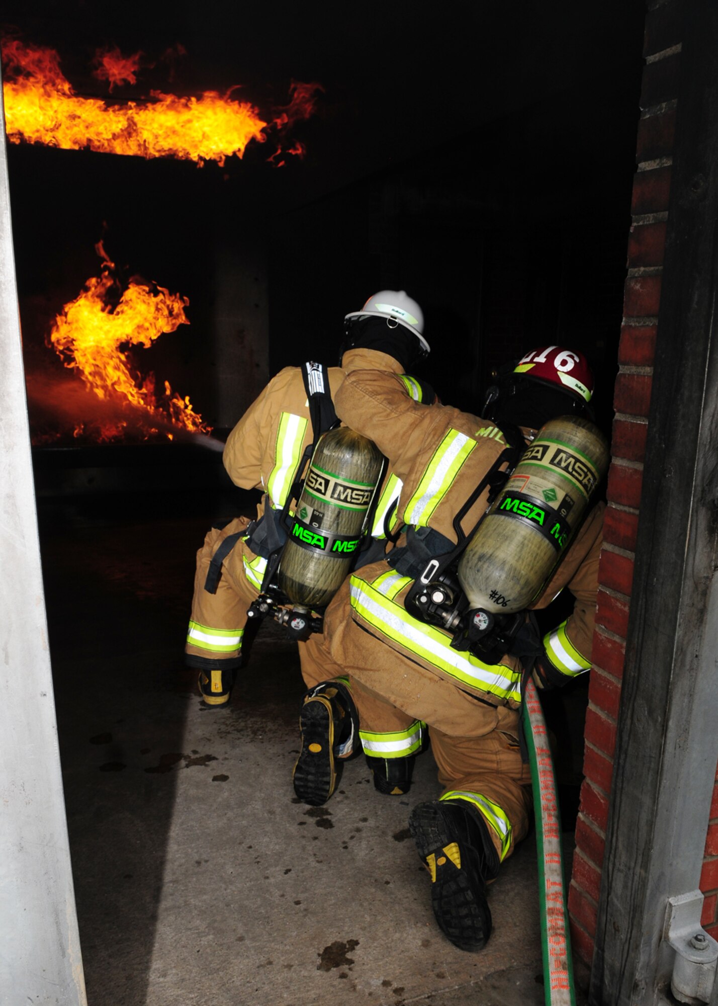 From left, Chief Master Sgt. Tracy Jones, 100th Air Refueling Wing command chief, and Staff Sgt. Noah Leiter, 100t Civil Engineer Squadron Fire Department firefighter, use a handline as they practice extinguishing a fire in the structural trainer April 25, 2013, at RAF Mildenhall, England. The 100th ARW command chief took part in the “dirty jobs” program, training with the firefighters to get an insight into what they do to support the mission. (U.S. Air Force photo by Karen Abeyasekere/Released)