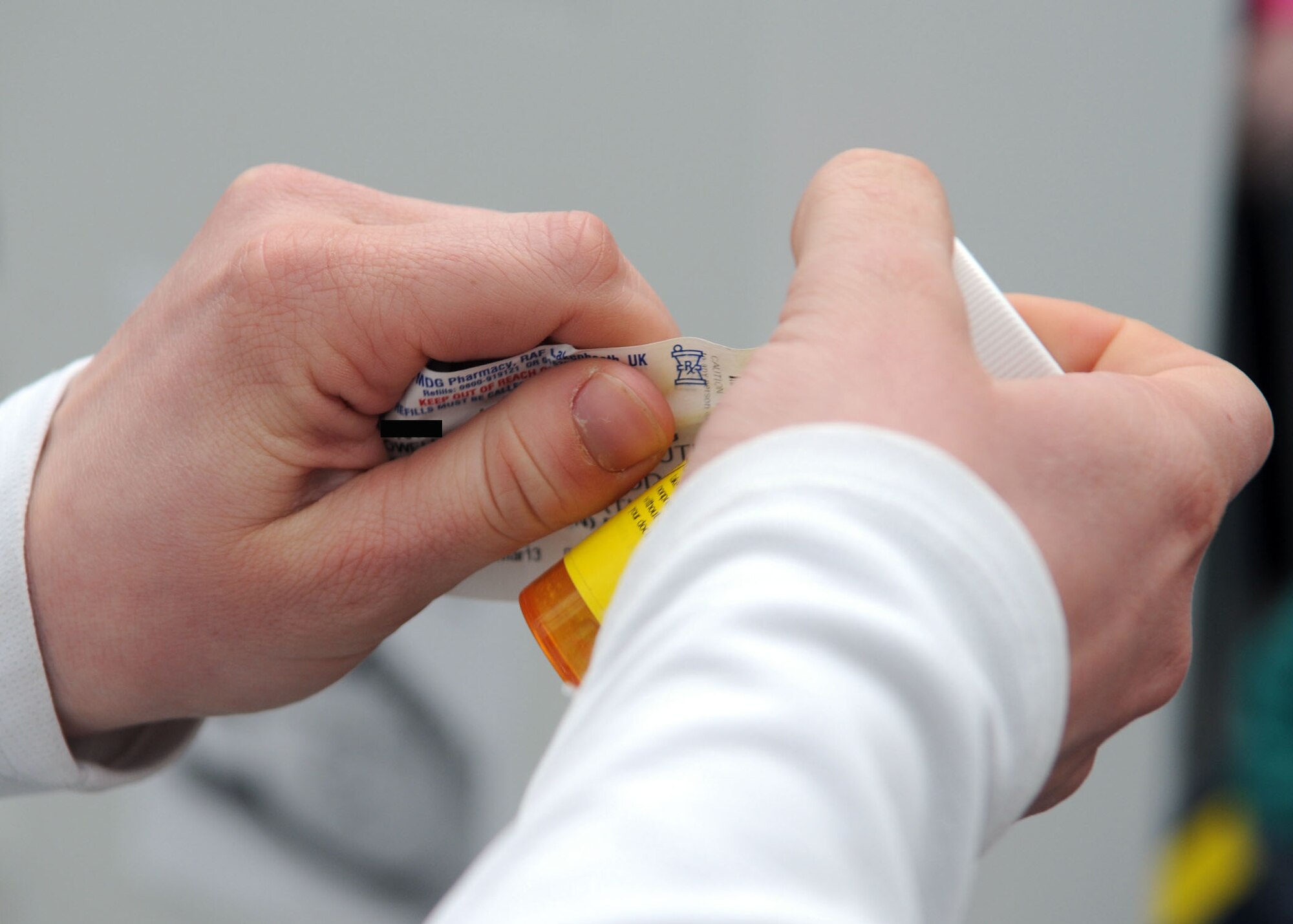 Staff Sgt. Amanda McDowell, 100th Communication Squadron cyber defense team technician, removes the label from a prescription before turning it in to the RAF Mildenhall Drug Demand Reduction program drug disposal table at The Exchange April 27, 2013, at RAF Mildenhall, England.  The DDR program collected more than 20 pounds of unused or expired medications. [(Photo altered for privacy purposes.)(U.S. Air Force photo by Staff Sgt. Tabitha M. Lee/Released)]