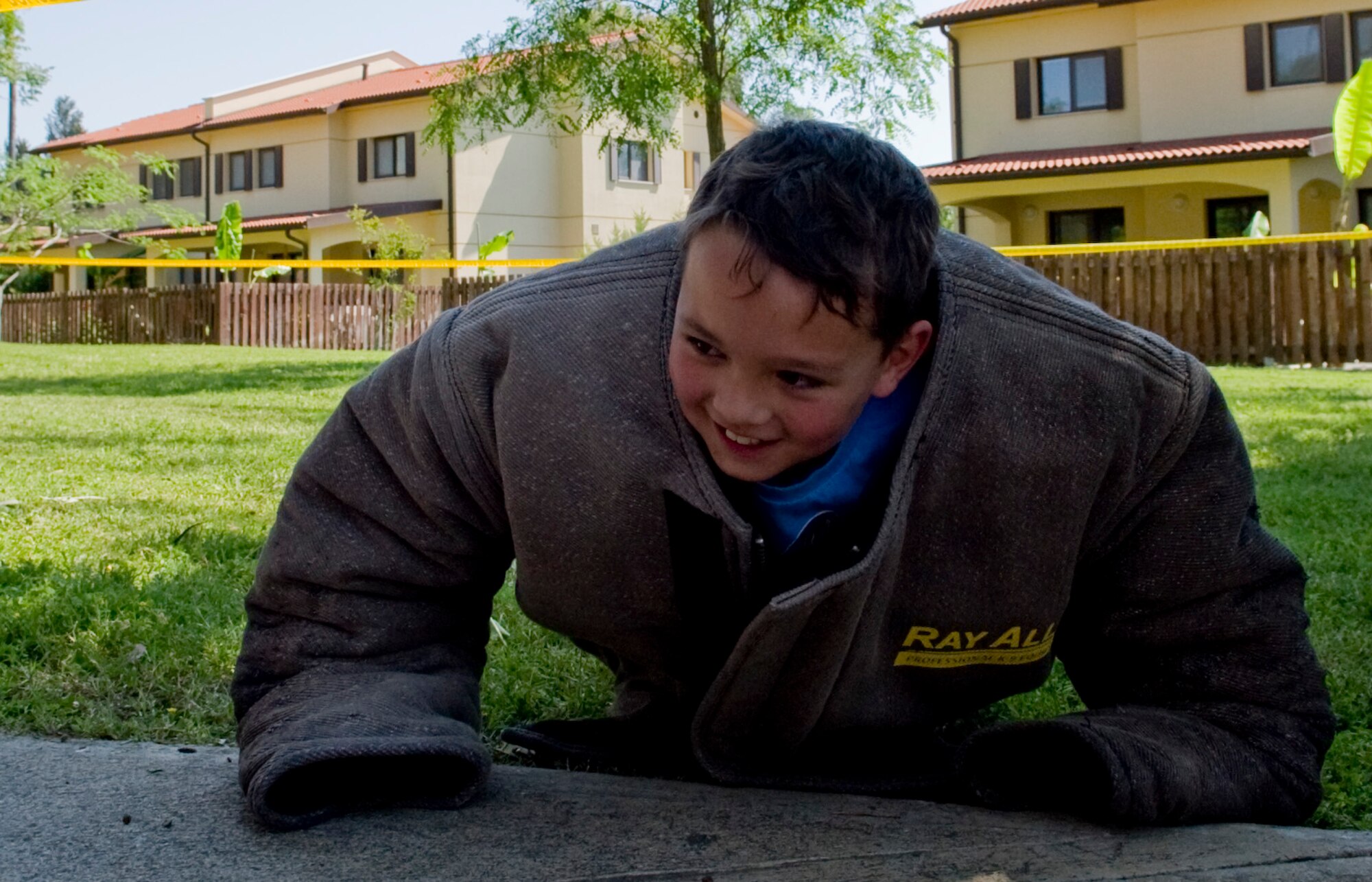 A child tries to do a push-up while wearing Military Working Dog handler’s training gear during the Spring-A-Palooza April 27, 2013, at Incirlik Air Base, Turkey. Spring-A-Palooza is an event to celebrate the Month of the Military Child. (U.S. Air Force photo by Staff Sgt. Veuril McDavid/Released)
