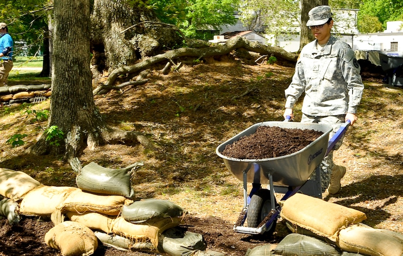 U.S. Army Pfc. Ana Barraza, McDonald Army Health Center dental assistant, pushes a wheelbarrow full of mulch at the Warwick Pier historical site during Earth Week events at Fort Eustis, Va., April 26, 2013. Volunteers spread mulch in an effort to reconstitute soil lost by erosion over time. (U.S. Air Force photo by Staff Sgt. Wesley Farnsworth / Released)