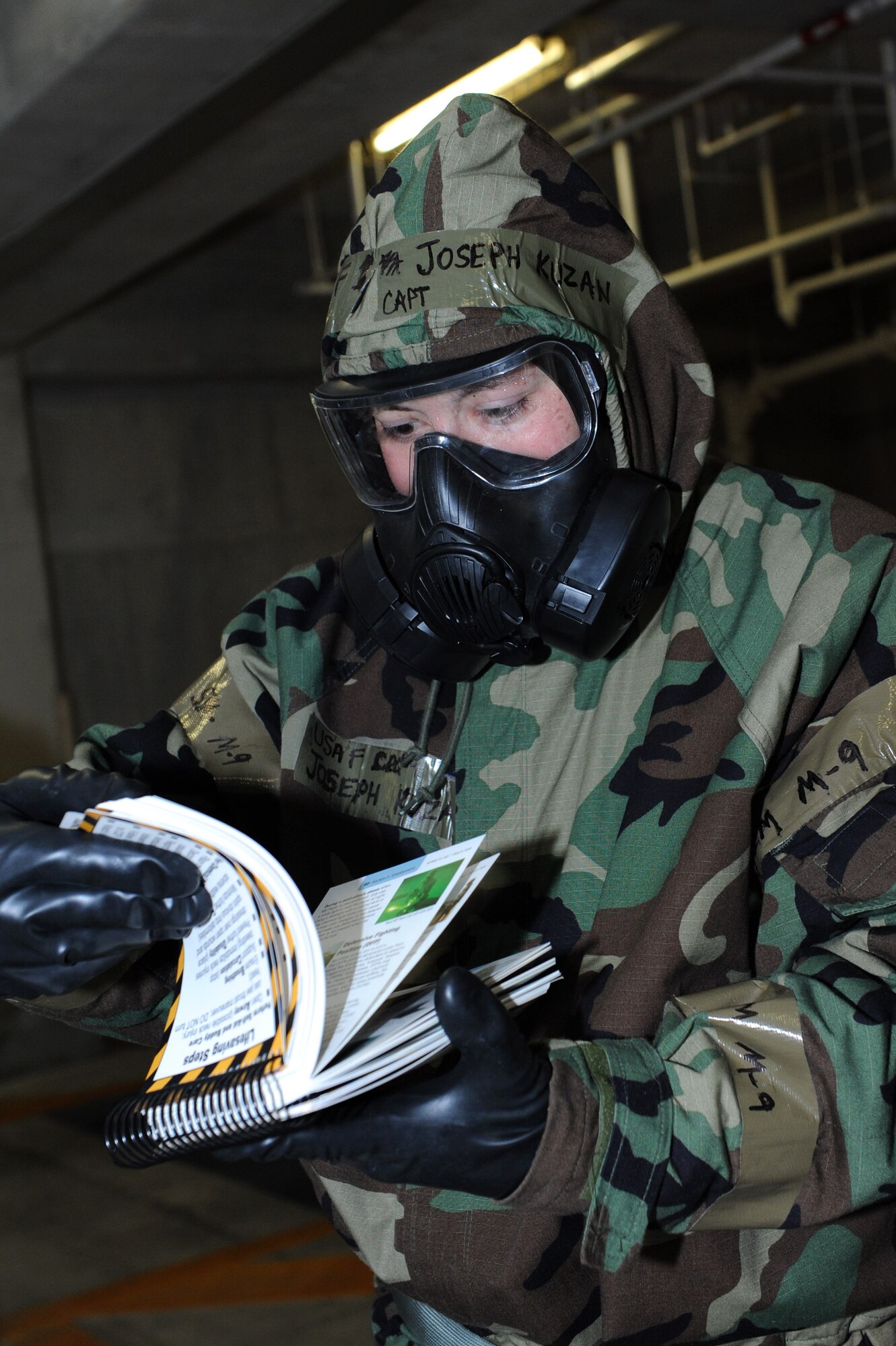 U.S. Air Force Capt. Joseph Kuzan, 18th Mission Support Group executive officer, checks an Airman's manual during an Ability to Survive and Operate Rodeo on Kadena Air Base, Japan, April 25, 2013. Personnel of the 18th MSG trained during the ATSO Rodeo, a training exercise event, on how to perform in a chemical environment, wrap assets and transition from a contaminated zone to a non-contaminated zone after a chemical attack. This exercise provided extra training to allow Airmen to improve their skills in order to survive during a contingency. (U.S. Air Force photo by Airman 1st Class Hailey R. Davis/Released) 