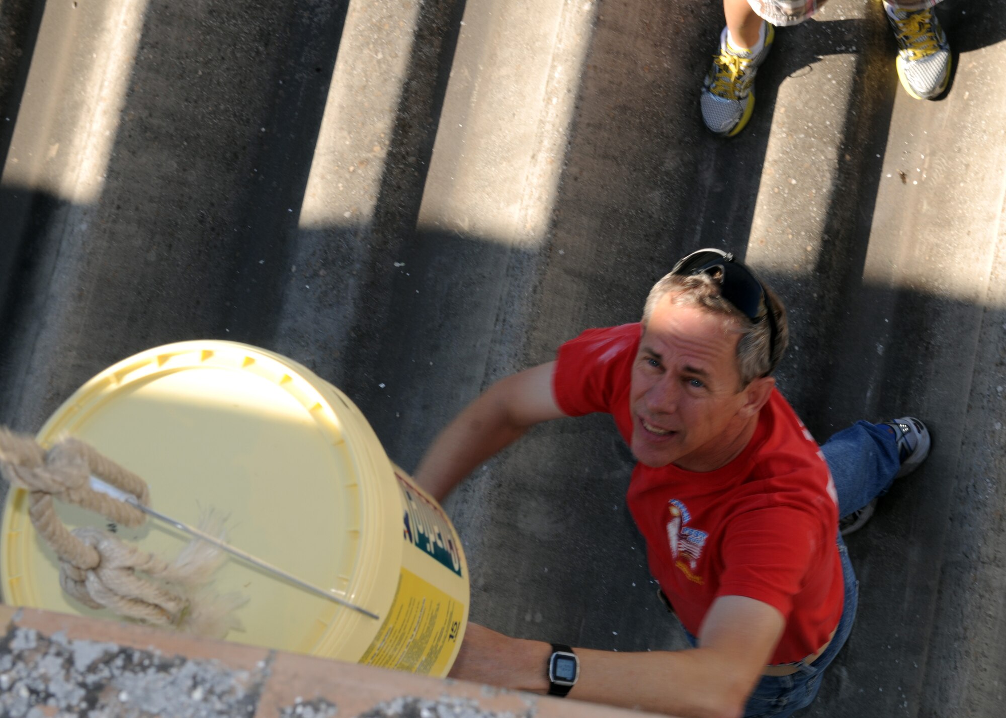 Airmen from the 100th Air Refueling Wing hoist a bucket of paint used to revitalize the walls of a convent for local children April 25, 2013, in Southwest Europe. The Airmen took the opportunity to give their time back to the local community and provide some necessary maintenance to the convent grounds. (U.S. Air Force photo by 1st Lt. Christopher Mesnard/Released)