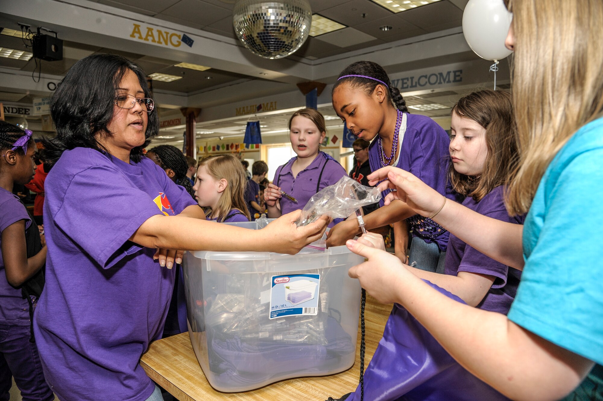 Anagerlie Davis, 354th Force Support Squadron youth programmer, hands out purple back packs and pens to students from Ben Eielson High school and Robert M. Crawford Elementary at the youth center April 19, 2013, Eielson Air Force Base, Alaska.  The gifts were donated by the 4-H Youth Development Organization in Fairbanks.  (U.S. Air Force Photo by Airman 1st Class Peter Reft/Released)