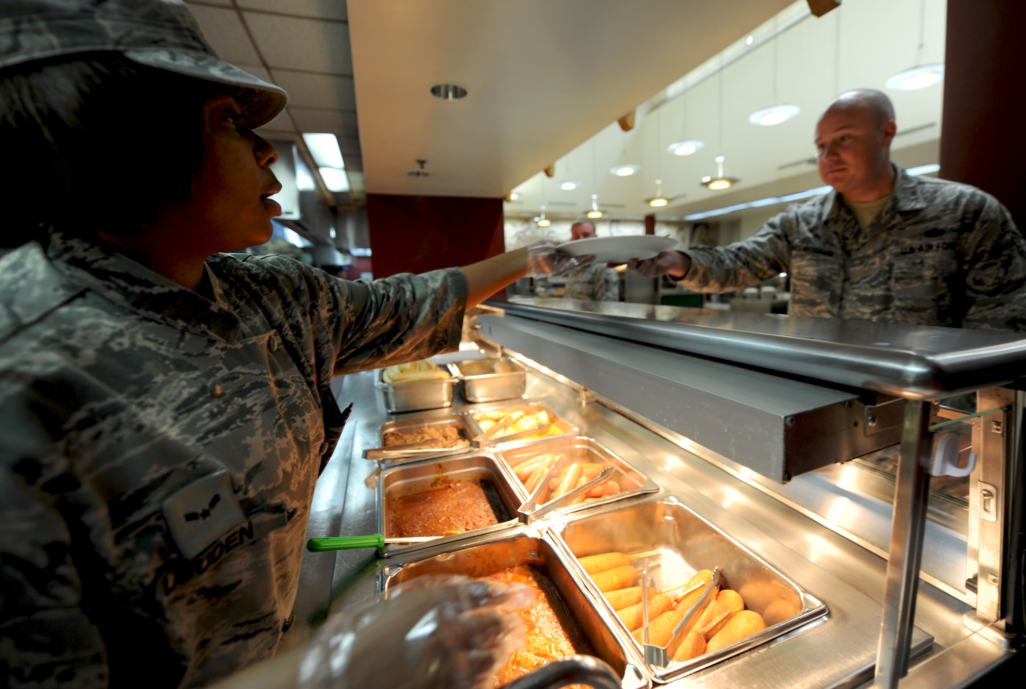 Airman 1st  Class Rayshon Louden, 51st Force Support Squadron food apprentice, serves a customer at the Ginko Tree dining facility at Osan Air Base, Republic of Korea April 23, 2013. The Ginko Tree prepares meals for more than 1300 members daily. (U.S. Air Force photo/Staff Sgt. Sara Csurilla)