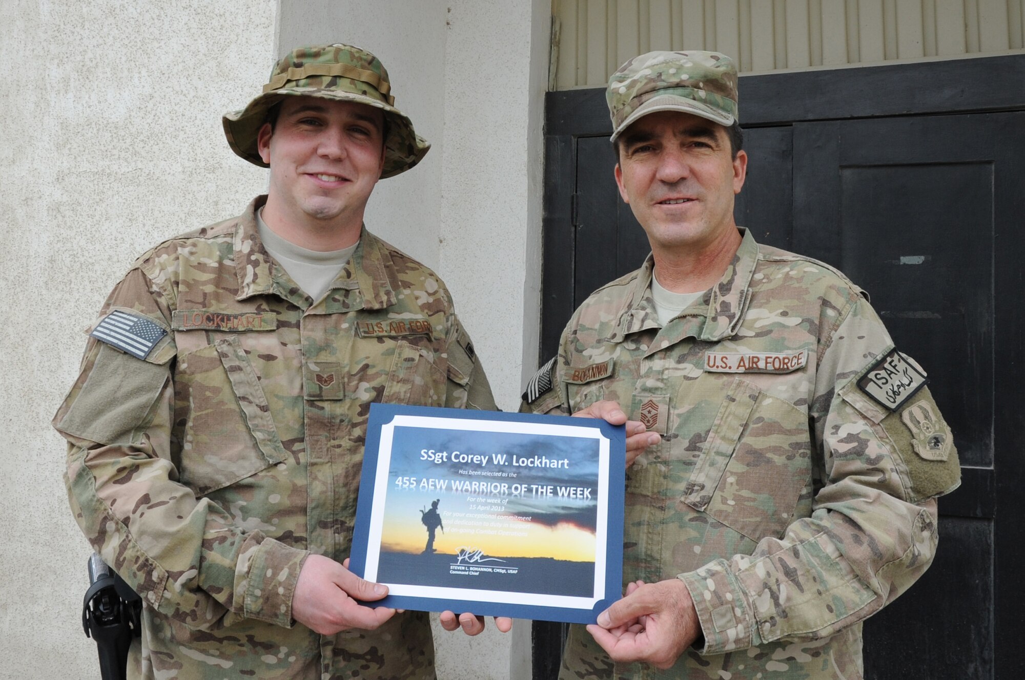 Chief Master Sgt. Steve Bohannon, Command Chief Master Sergeant of the 455th Air Expeditionary Wing, presents the "Warrior of the Week" award to Staff Sgt. Corey Lockhart, 455th Expeditionary Security Forces Squadron fly-away security coordinator assistant NCO in charge, on Bagram Airfield, Afghanistan, April 24, 2013. Lockhart directed the operations of 25 Fly-Away Security Team members responsible for protecting 3,000 personnel and 5,000 tons of cargo. (U.S. Air Force photo/Staff Sgt. David Dobrydney)