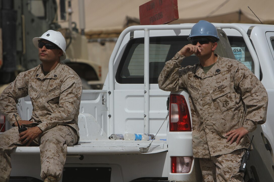 Staff Sgt. Osman Mendoza, the 8th Communications Battalion transmission chief, left and Petty Officer 2nd Class David Rodriguez, the battalion's corpsman, keep an eye on battalion's Marines conducting preventative maintenance on equipment on the communications tower. Four Marines are solely responsible for maintaining Internet and phone services by either conducting preventative maintenance or repairing communication devices on the tower.