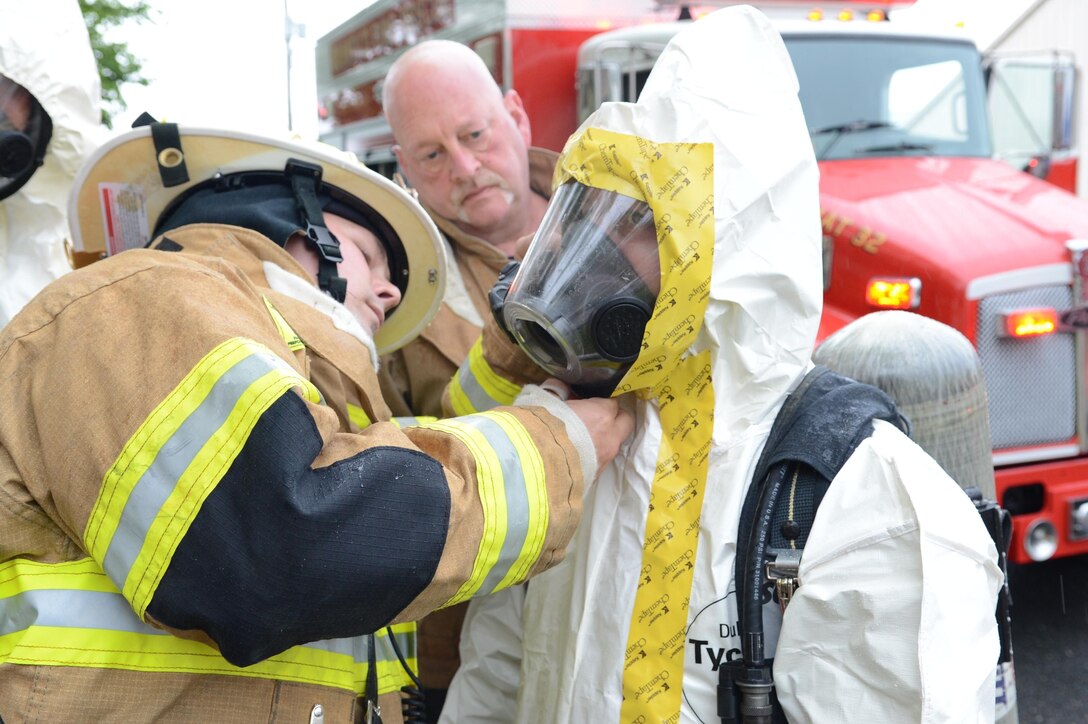 Ulysses Taormina, assistant chief, Marine Corps Base Quantico Fire Department and Emergency Rescue, leans in to help Shannon Publicover, firefighter/paramedic, tape up her hazardous materials suit during a suspicious package situation at the military side of the Post Office April 29, 2013. The four individuals who were exposed to the letter resumed their work and the post office reopened.