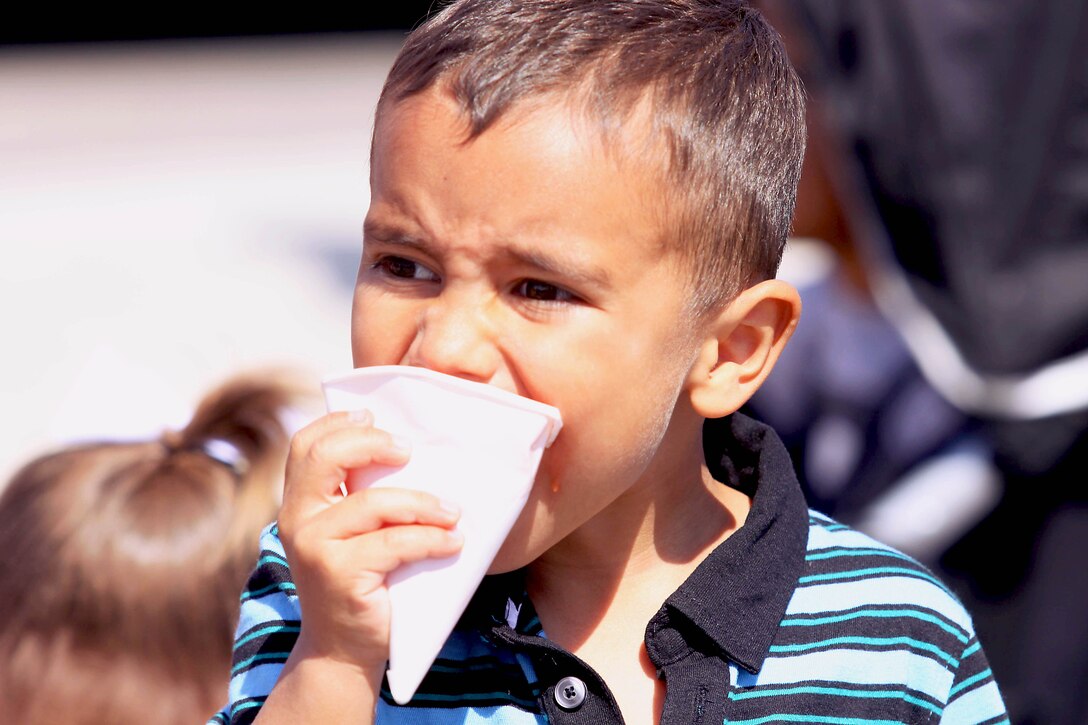 Four-year-old, Tristan bites into a snow cone, as it drips down his face,  during the 18 annual Kids First Fair hosted by Marine and Family Programs at the Paige Fieldhouse here April 27. The event provided live attractions, demonstrations and entertainment including pony rides, face painting and rock climbing.
