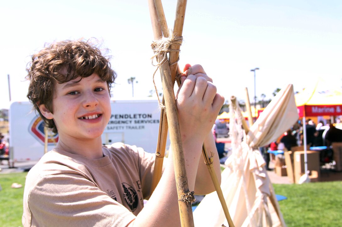Actor Nolan Gould wraps twine around bamboo sticks while making a tent during the 18th annual Kids First Fair hosted by Marine and Family Programs at the Paige Fieldhouse here April 27. The theme for this year’s event was “Kids are superheroes” and provided live attractions, demonstrations and entertainment including a pony rides, face painting and rock climbing for military youth. Gloud plays the role of Luke Dunphy on the ABC sitcom Modern Family.

