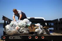 A volunteer collects trash that was gathered during the Splash for Trash event aboard Camp Lejeune, N.C., April 26, 2013. The trash was then loaded into a contractor dumpster. (U.S. Marine Corps photo by Lance Cpl. Shawn Valosin)