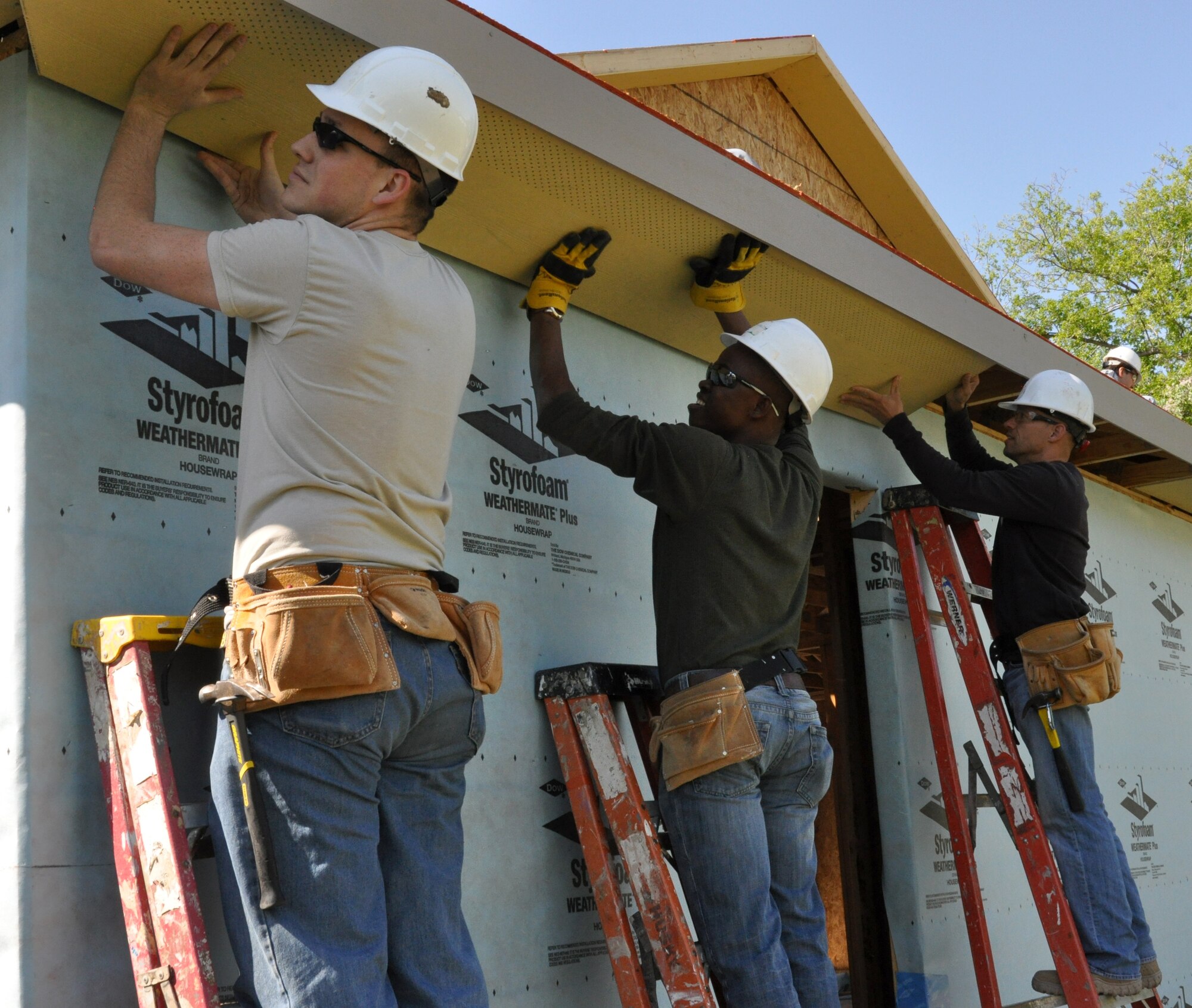 (left to right) Senior Airman Will Howell, 301st Aircraft Maintenance Squadron specialist, Chris, the future recipient of the house and Master Sergeant Gene Gaspar, 301st AMXS weapons expediter, are setting the panels to be nailed down.  Chris is originally from South Africa and has to contribute 250 volunteer hours in order to receive the house. These 301st AMXS members spent the day building a house for a local Fort Worth resident under the Habitat for Humanity program. (U.S. Air Force photo/Senior Airman Jeremy Roman)