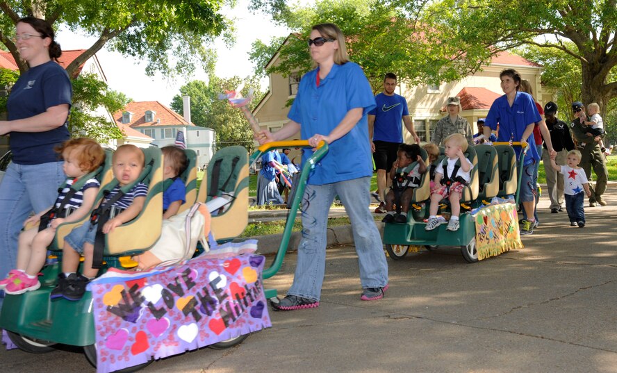 Child Development Center staff walk with children during the Month of the  Military Child Parade on Barksdale Air Force Base, La., April 30, 2013. Each year during the month of April, the Child Development Center here holds various events to celebrate military children, such as tree planting, a trike-a-thon, an art auction, a parent breakfast and parade. (U.S. Air Force photo/Airman 1st Class Andrew Moua)