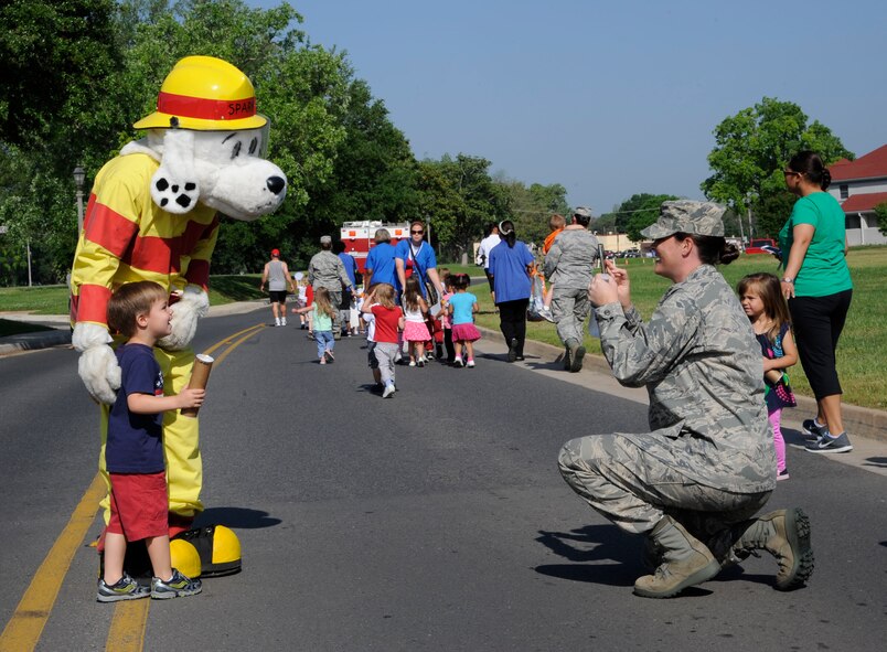 Maj. Heather Decker, 343rd Bomb Squadron, takes a photo of her son and Sparky during the Month of the Military Child parade on Barksdale Air Force Base, La., April 30, 2013. Each year during the month of April, the Child Development Center here holds various events to celebrate military children, such as tree planting, a trike-a-thon, an art auction, a parent breakfast and parade. (U.S. Air Force photo/Airman 1st Class Andrew Moua)