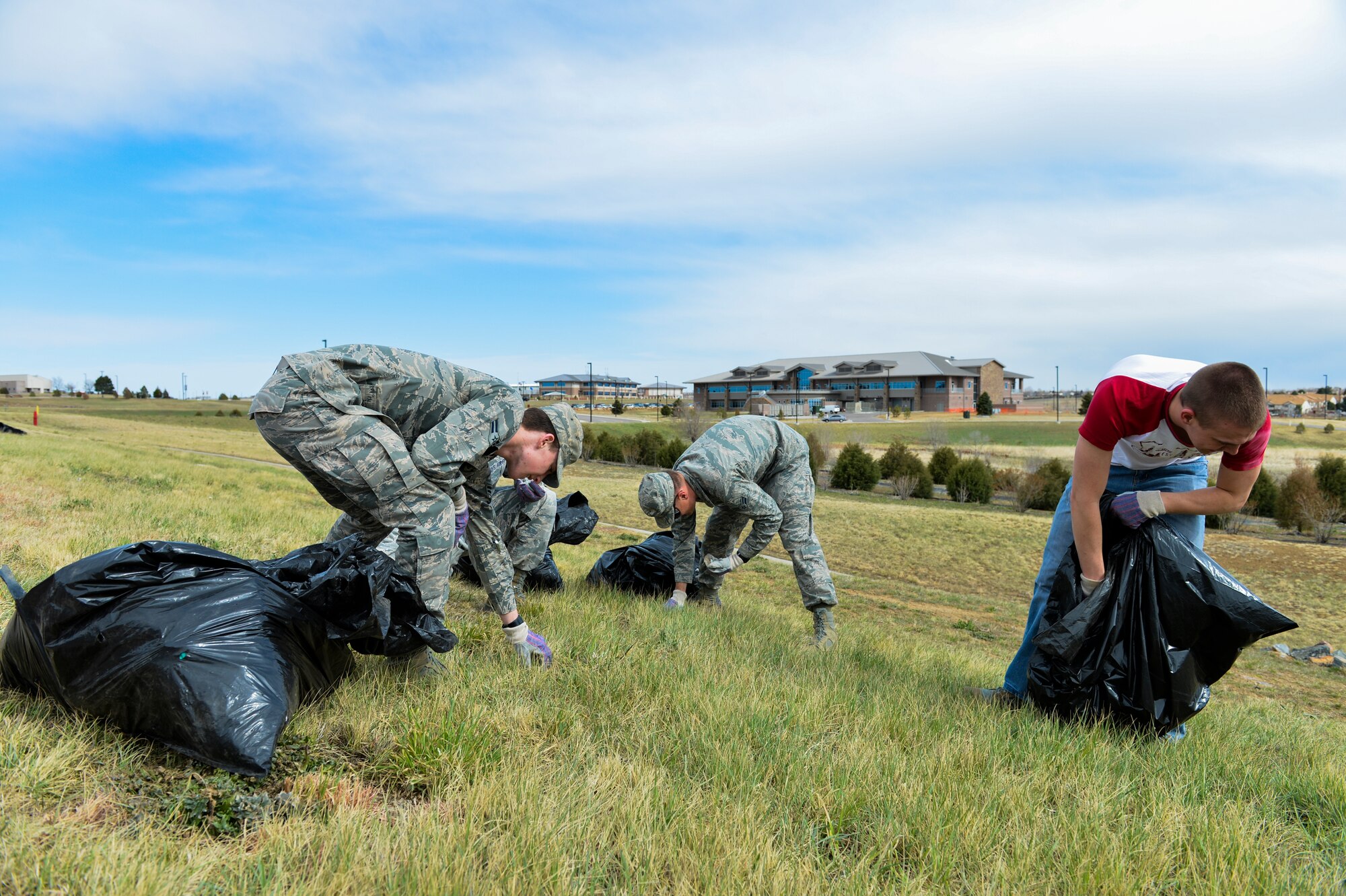 Team Buckley members work together to pick up litter around the base April 25, 2013, during the Buckley Earth Day site cleanup on Buckley Air Force Base, Colo. For more information on what the Air Force environment friendly initiatives, visit here http://www.afcec.af.mil/news/earthday2013/index.asp. (U.S. Air Force photo by Senior Airman Paul Labbe/Released)