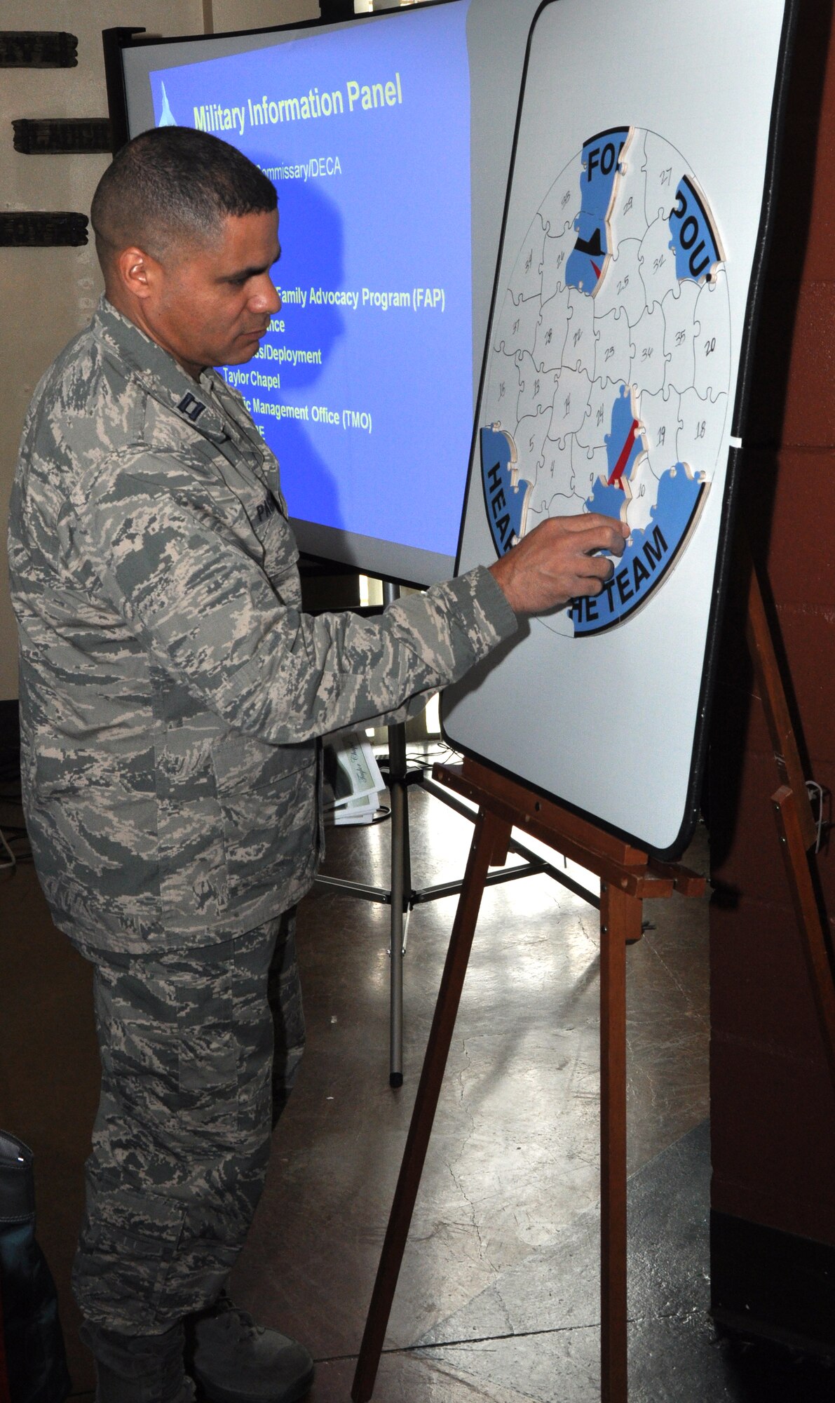 GOODFELLOW AIR FORCE BASE, Texas – Capt. Victor Pagan, 17th Training Wing chaplain, places a puzzle piece onto the Heartlink emblem at the Event Center here, April 25. Pagan and other agency representatives placed puzzle pieces on the board after their briefings, so spouses can see they are a part of the picture. (U.S. Air Force photo/ Airman 1st Class Joshua Edwards)