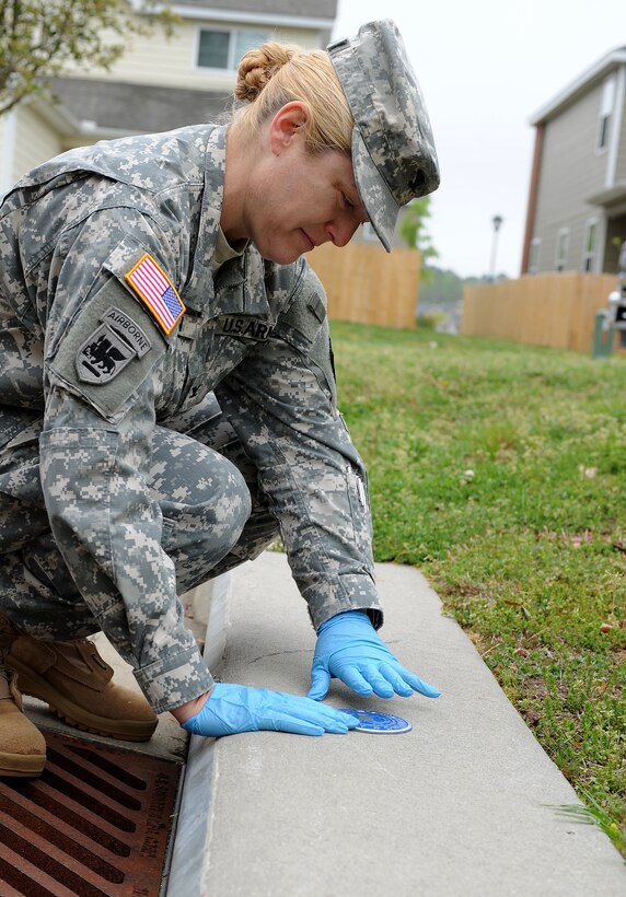 U.S. Army Col. Jayne V. Jansen, 633rd Air Base Wing vice commander, glues a medallion above a storm drain in bethel Manor’s Jamestown Village, Va., April 24, 2013. The medallion installation was one of many activities hosted by Joint-Base Langley-Eustis during Earth Week. (U.S. Air Force photo by Senior Airman Teresa Aber/Released)