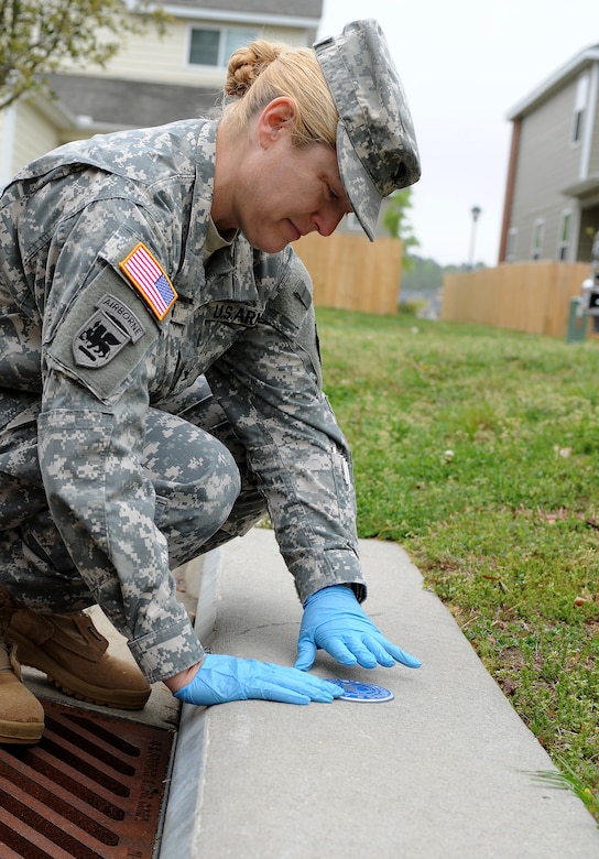 U.S. Army Col. Jayne V. Jansen, 633rd Air Base Wing vice commander, glues a medallion above a storm drain in bethel Manor’s Jamestown Village, Va., April 24, 2013. The medallion installation was one of many activities hosted by Joint-Base Langley-Eustis during Earth Week. (U.S. Air Force photo by Senior Airman Teresa Aber/Released)