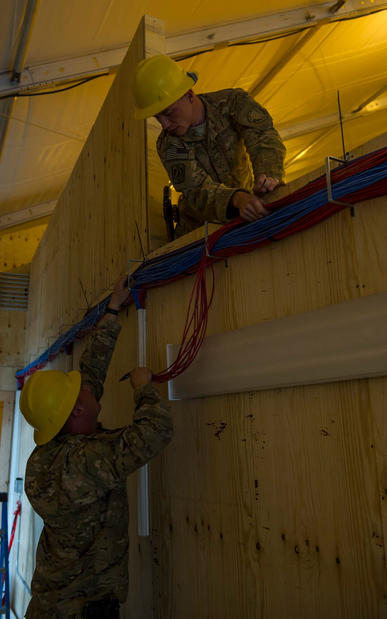 U.S. Air Force Staff Sgt. Kevin Rochat, left, 160th Theater Signal Support Brigade radio frequency transmissions journeyman and Staff Sgt. Andrew Mielcarek, right, 160th Theater Signal Support Brigade cable and antenna systems craftsman, runs telephone and computer cable in a Joint Operation Center, March 19, 2013, at Bagram Airfield, Afghanistan. Rochat and Mielcarek are members of an Air National Guard Engineering & Installation Team deployed from the 219th Engineering Installation Squadron, Tulsa, Oklahoma. Meilcarek is a native of Tulsa, Oklahoma. Rochat is a native of Oklahoma City, Oklahoma. (U.S. Air Force photo by Staff Sgt. Marleah Miller)
