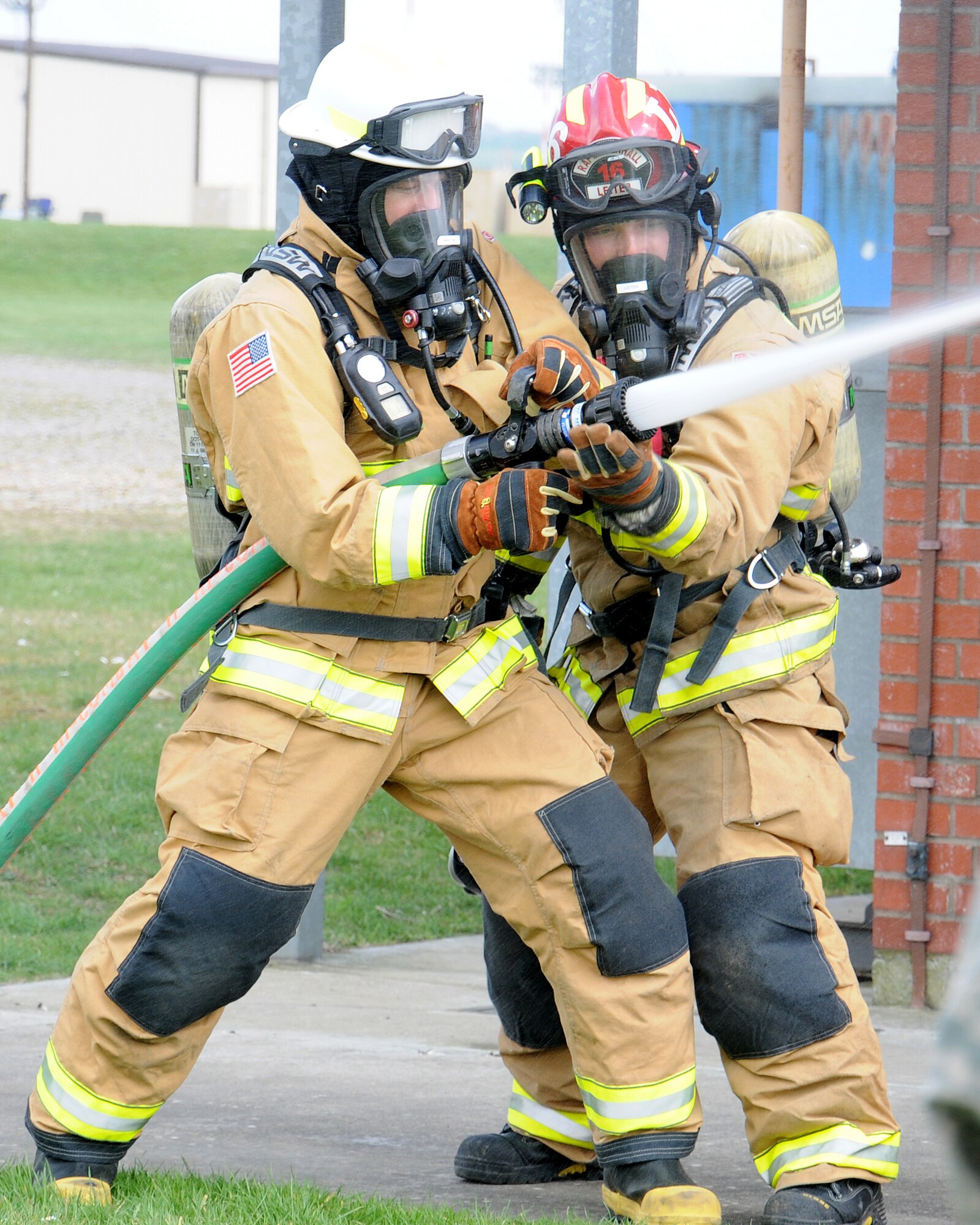 From left, Chief Master Sgt. Tracy Jones, 100th Air Refueling Wing command chief, operates a fire hose during training with Staff Sgt. Noah Leiter, 100th Civil Engineer Squadron Fire Department firefighter from Carthage, Mo., April 25, 2013, at RAF Mildenhall, England. The firefighters showed Jones how they do their job as part of a “dirty jobs” initiative. The task force tip nozzle was "mid-force" at 70 to 200 gallons per minute, 100 pounds per square inch (75 psi for low pressure). (U.S. Air Force photo by Gina Randall/Released)