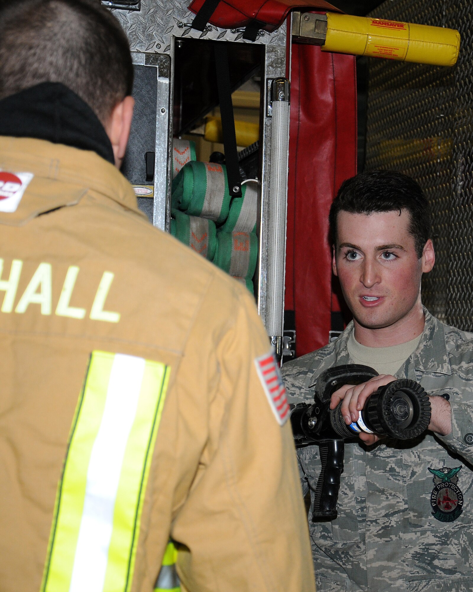 From right, Airman 1st Class Kevin Brittan, 100th Civil Engineer Squadron Fire Department firefighter from Lindenhurst, N.Y., explains to Chief Master Sgt. Tracy Jones, 100th Air Refueling Wing command chief, how to safely reel out a fire hose and operate it, April 25, 2013, at RAF Mildenhall, England. The firefighters showed Jones how they do their job as part of a “dirty jobs” initiative. The hose pressure was tested at 400 pounds per square inch, service pressure 200 psi. (U.S. Air Force photo by Gina Randall/Released)