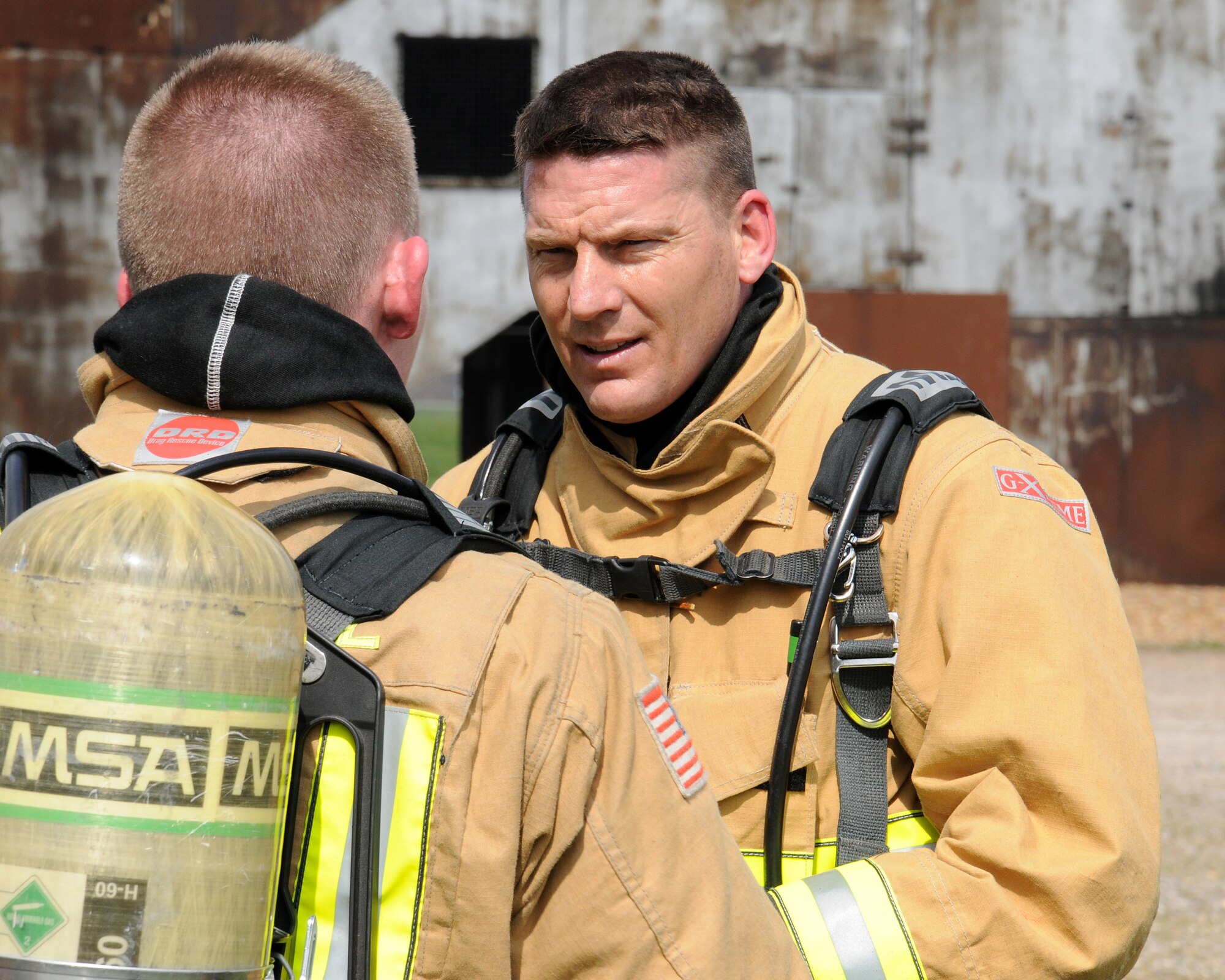 From left, Staff Sgt. Noah Leiter, 100th Civil Engineer Squadron Fire Department firefighter from Carthage, Mo., debriefs Chief Master Sgt. Tracy Jones, 100th Air Refueling Wing command chief, on his skills as a firefighter following a training exercise, April 25, 2013, at RAF Mildenhall, England. The fire department personnel showed Jones how they do their job as part of a “dirty jobs” initiative. With events such as this, the command chief can stay in tune with the Airmen in various specialties on base. (U.S. Air Force photo by Gina Randall/Released)