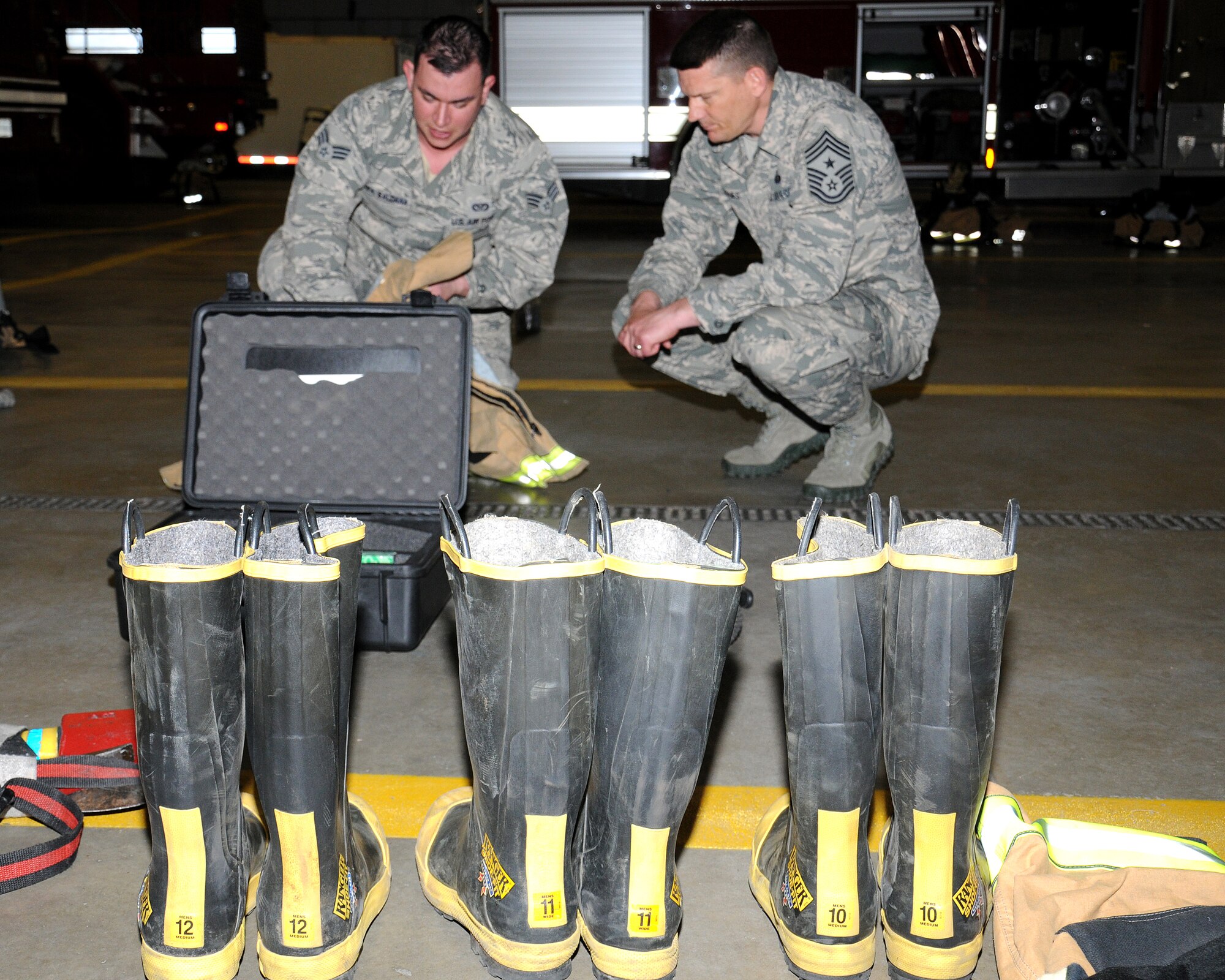 From left, Senior Airman Noel Rivera Saldana, 100th Civil Engineer Squadron Fire Department firefighter from Caguas, Puerto Rico, discusses the proper wear of safety clothing with Chief Master Sgt. Tracy Jones, 100th Air Refueling Wing command chief, April 25, 2013, at RAF Mildenhall, England. The command chief took part in the “dirty jobs” initiative where the fire department personnel showed him how they do their job. Jones learned how to use protective clothing and equipment prior to going to the fire trainer. (U.S. Air Force photo by Gina Randall/Released)