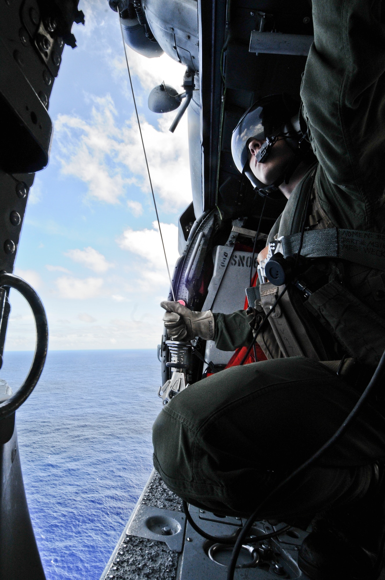 Petty Officer 2nd Class Lucas Voie, Helicopter Sea Combat Squadron 25 aircrewman, prepares to lower a line to a rescue swimmer in the water below during joint water rescue training near Sirena Beach on Andersen Air Force Base, Guam, April 25, 2013. 
