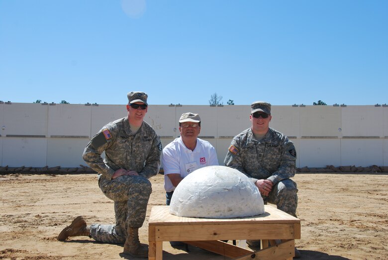 Dr. Paul Mlakar, Engineer Research and Development Center, and West Point Mechanical Engineering Cadets kneel behind an explosive charge used to demonstrate their project for the protection of deployed soldiers.