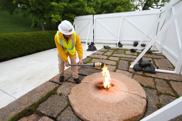 ARLINGTON, Va. – Randy Barton, an Arlington National Cemetery engineering technician, lights a torch from the John F. Kennedy Eternal Flame April 29, 2013. The torch was used to transfer the flame to a temporary burner while the permanent flame undergoes repair and upgrade work to install new burners, a new igniter as well as new gas and air lines. (U.S. Army photo/Patrick Bloodgood)