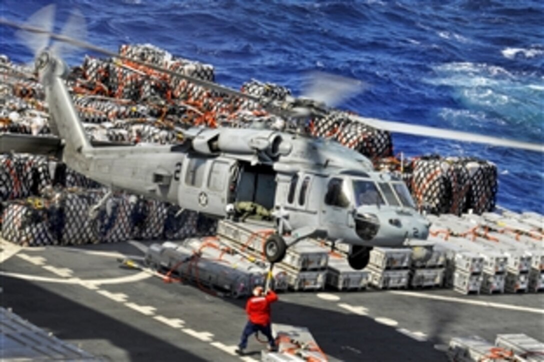 A U.S. sailor aboard the Military Sealift Command dry cargo and ammunition ship USNS Richard E. Byrd attaches cargo to an MH-60S Seahawk helicopter while conducting a replenishment with the aircraft carrier USS Nimitz underway in the Pacific Ocean, April 28, 2013. The Seahawk is assigned to Helicopter Sea Combat Squadron 6. 