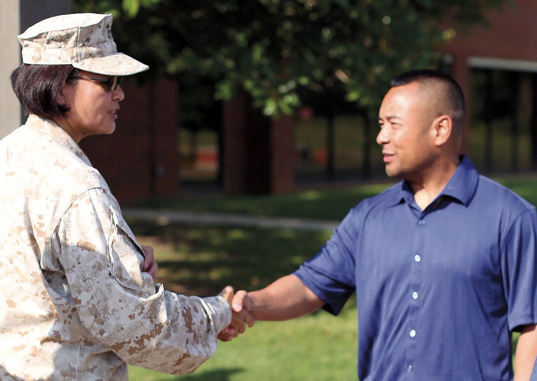 Master Gunnery Sgt. Paz T. Platt, left, of Marine Corps Logistics Command welcomes Maj. Jose M. Tee back with a handshake after his deployment to Afghanistan, July 25.