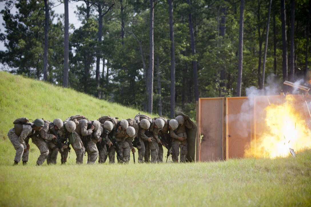Marines with 2nd and 4th Combat Engineer Battalions and 8th Engineer Support Bn. take cover behind a blast blanket during a breaching explosion here, July 24. Marines, all participants of the Sapper Leaders Course, spent one day executing urban demolition in order to learn advanced combat engineer tactics, techniques, and procedures. The course was the first of its kind, allowing Reserve and active-duty Marines to receive advanced training in their MOS. 