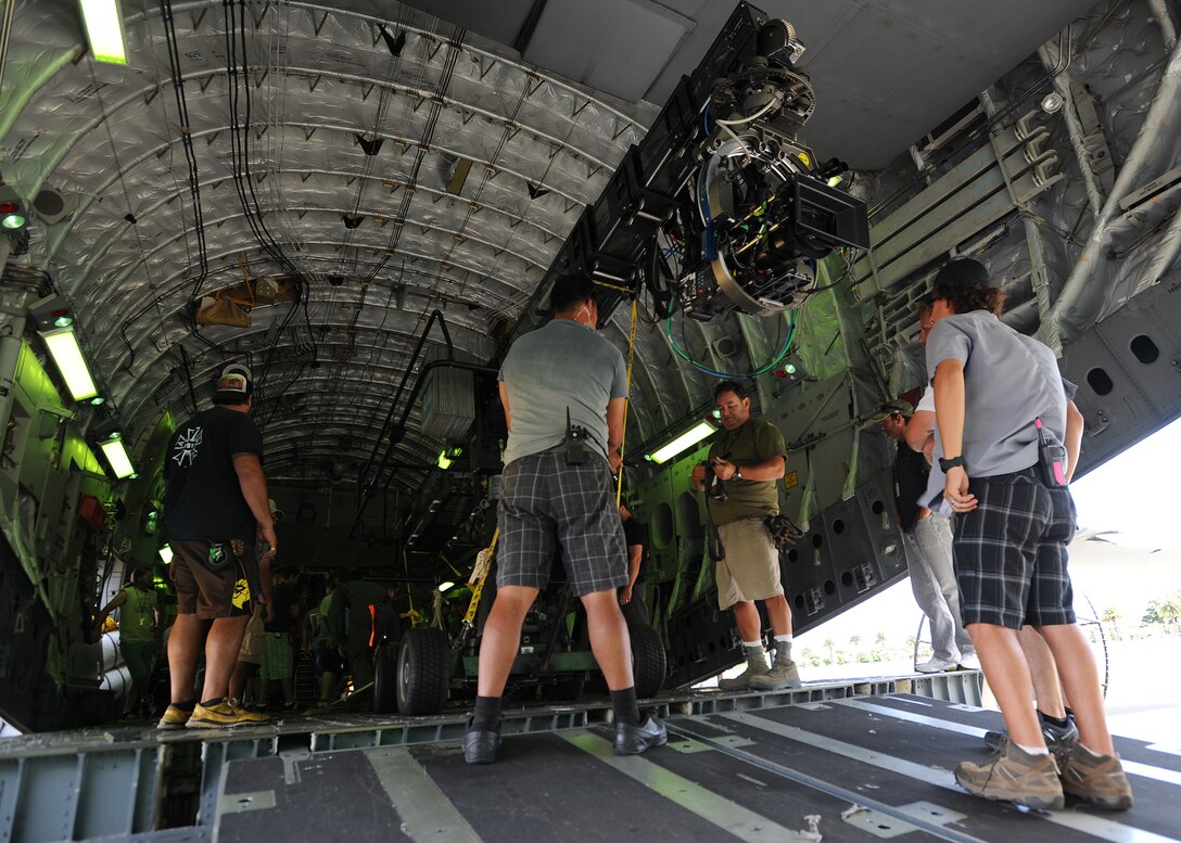 Production crew members from a major motion picture unload a camera from a 535th Airlift Squadron C-17 Globemaster III at Joint Base Pearl Harbor-Hickam, July 1, 2013.  Members from the 535th AS received a rare opportunity to work hand and hand with the movie’s production crew. (U.S. Air Force photo/Tech. Sgt. Jerome S. Tayborn)