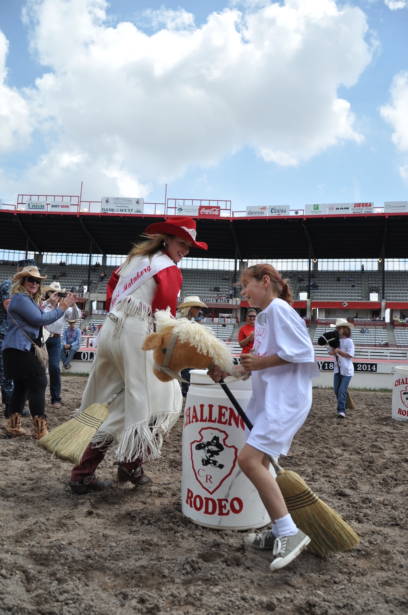 Kaci Malmborg, the 2013 Cheyenne Frontier Days Lady-in-Waiting, and a child practice barrel racing while using broom horses July 24, 2013, during the Cheyenne Frontier Days Challenge Rodeo event held in Frontier Park, Cheyenne, Wyo. Challenge Rodeo offers the chance for special-needs children to take part in the annual CFD rodeo. Trophies are presented to all contestants after each day of the two-day event. (U.S. Air Force photo by Senior Airman Mike Tryon)