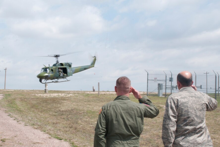 Lieutenant Col. Bob Ewers, 320th Missile Squadron commander, and Col. Trevor Flint, 90th Maintenance Group commander, salute as Maj. Gen. Michael Carey, 20th Air Force commander, and departs from the Foxtrot-01 Missile Alert Facility in a UH-1N helicopter July 29, 2013. (U.S. Air Force photo by Airman 1st Class Jason Wiese)