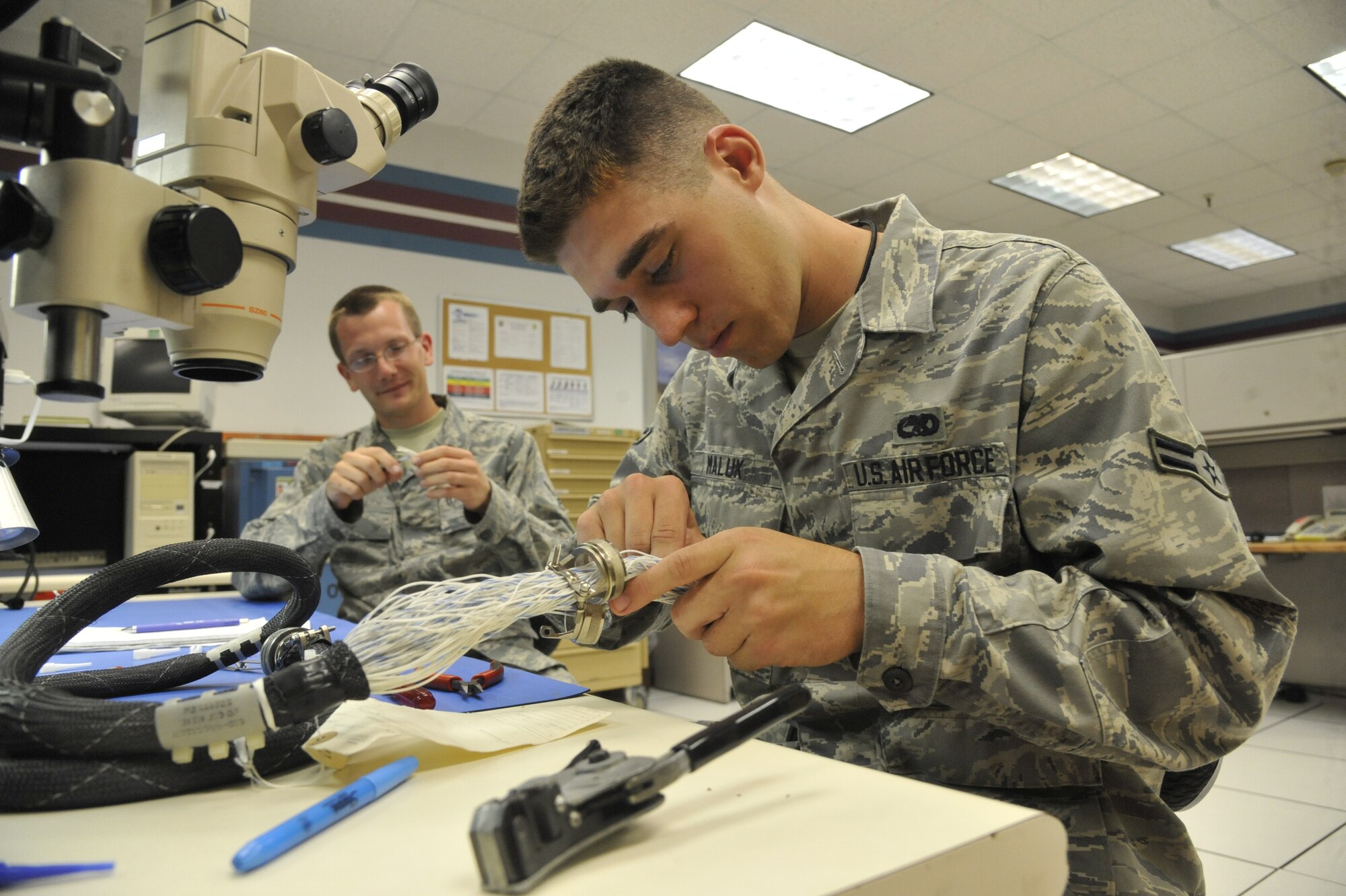 Airmen 1st Class James Lott and Michael Maluk, 509th Maintenance Squadron avionics back shop team members, remove and replace the back shell on a cannon plug at Whiteman Air Force Base, Mo., July 25, 2013. Stress over time, as well as normal wear, can cause back shells to break, requiring removal and replacing. (U.S. Air Force photo by Airman 1st Class Keenan Berry/Released)