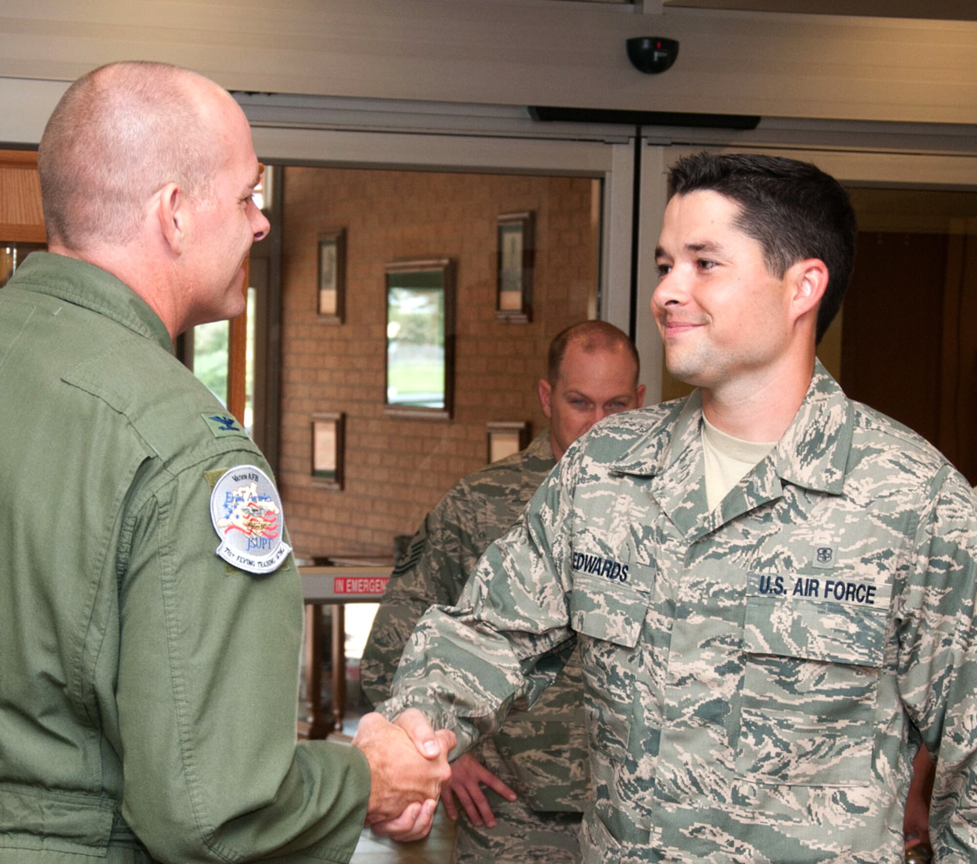 The 71st Flying Training Wing commander, Col. Darren James, left, congratulates Senior Airman Layton Edwards for his selection as the July Airman of the Month at Vance Air Force Base, Okla. (U.S. Air Force photo/ Senior Airman Frank Casciotta)